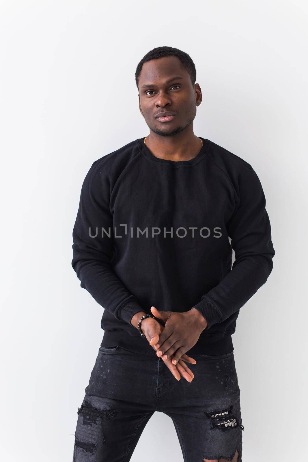 Handsome African American man posing in black sweatshirt on a white background. Youth street fashion photo with afro hairstyle. by Satura86