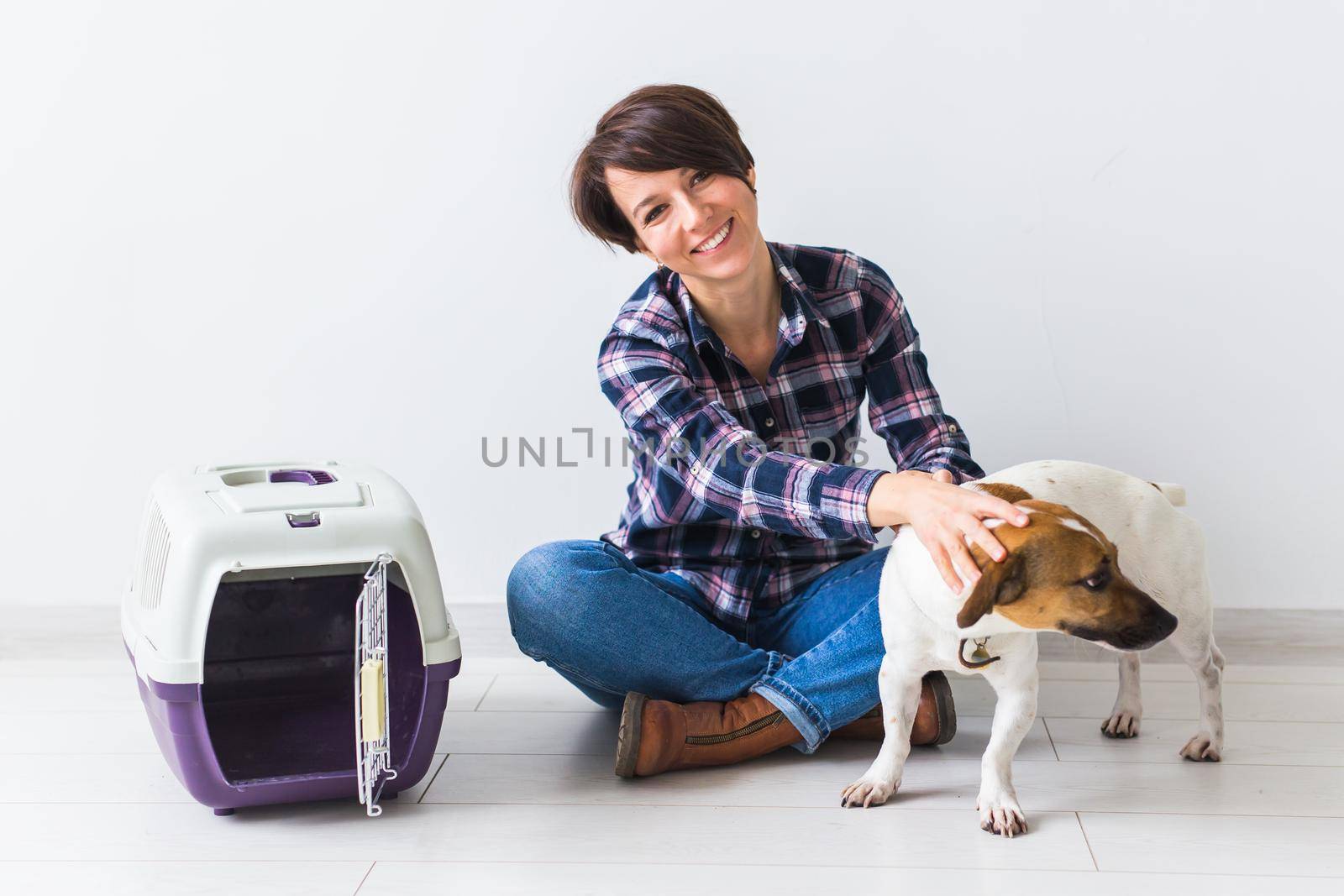 Dog carrying bags and pets owner concept - Attractive cheerful female in plaid shirt holds favourite pet. Happy woman with her jack russell terrier by Satura86