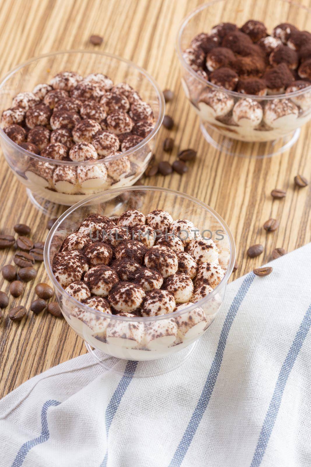 Tiramisu dessert in a glass cup on wooden table close up