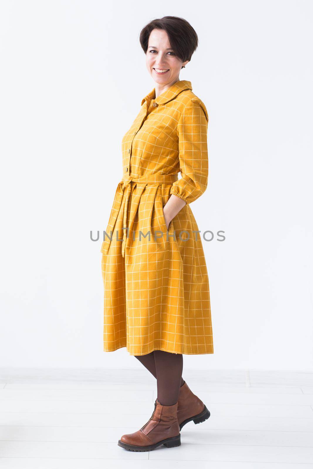 clothing, designer, people concept - back view of attractive woman in a yellow dress posing on white room