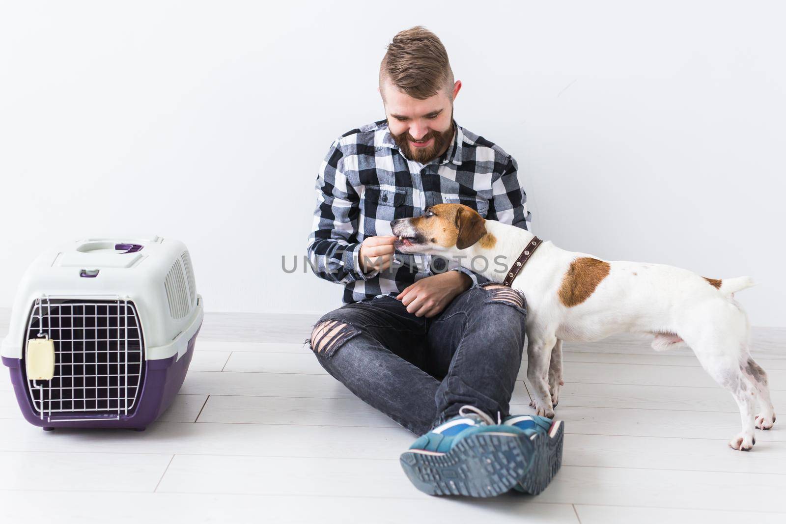 Dog carrying bags and pets owner concept - Attractive cheerful male in plaid shirt holds favourite pet. Happy bearded man with his jack russell terrier by Satura86