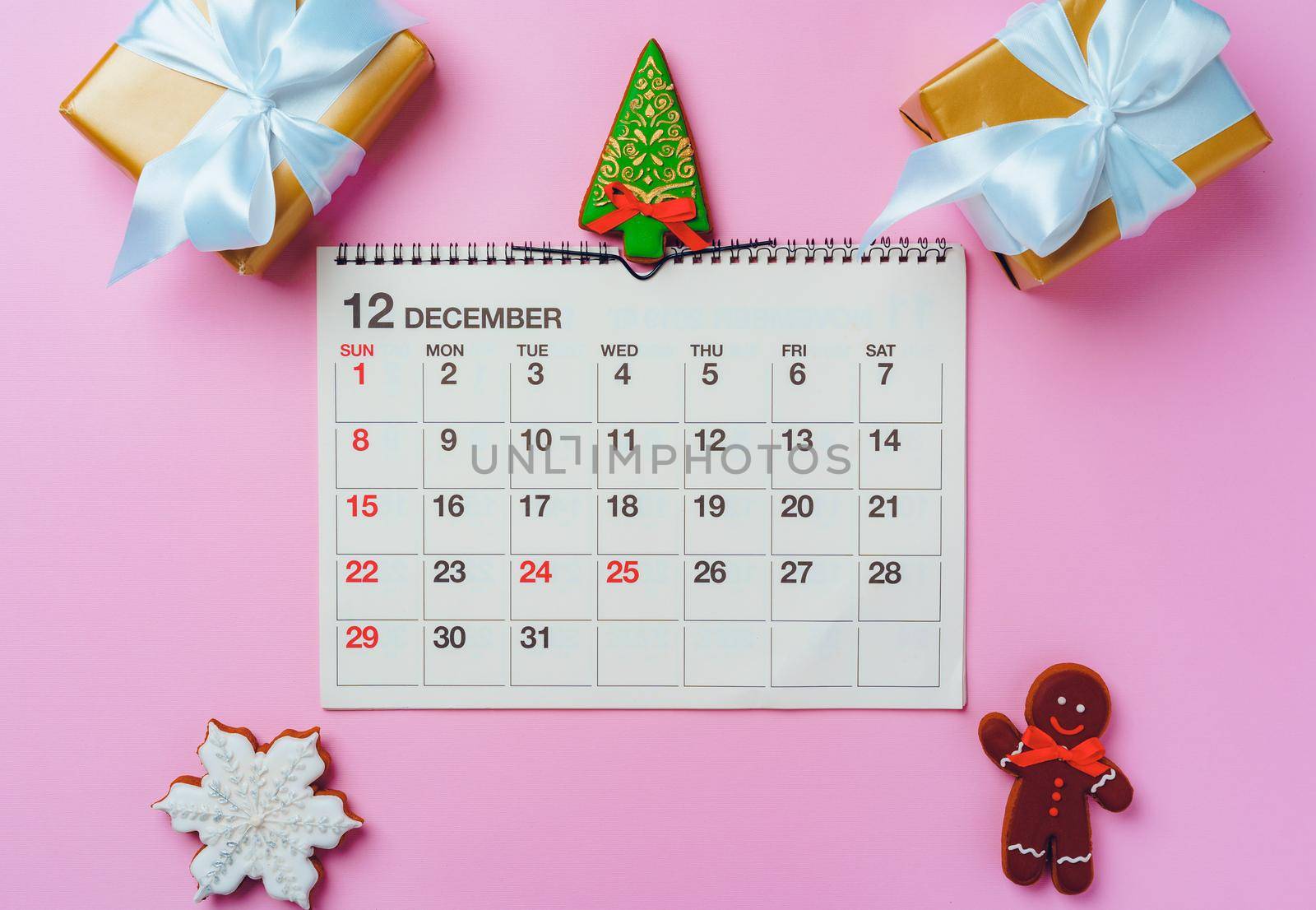 Calendar page of december with festive decorations on pink background, top view