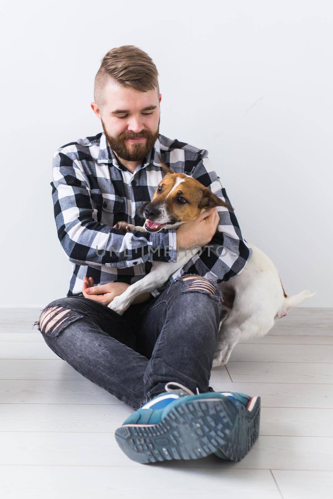 Pets owner concept - Attractive cheerful male in plaid shirt holds favourite pet. Happy bearded man with his jack russell terrier by Satura86