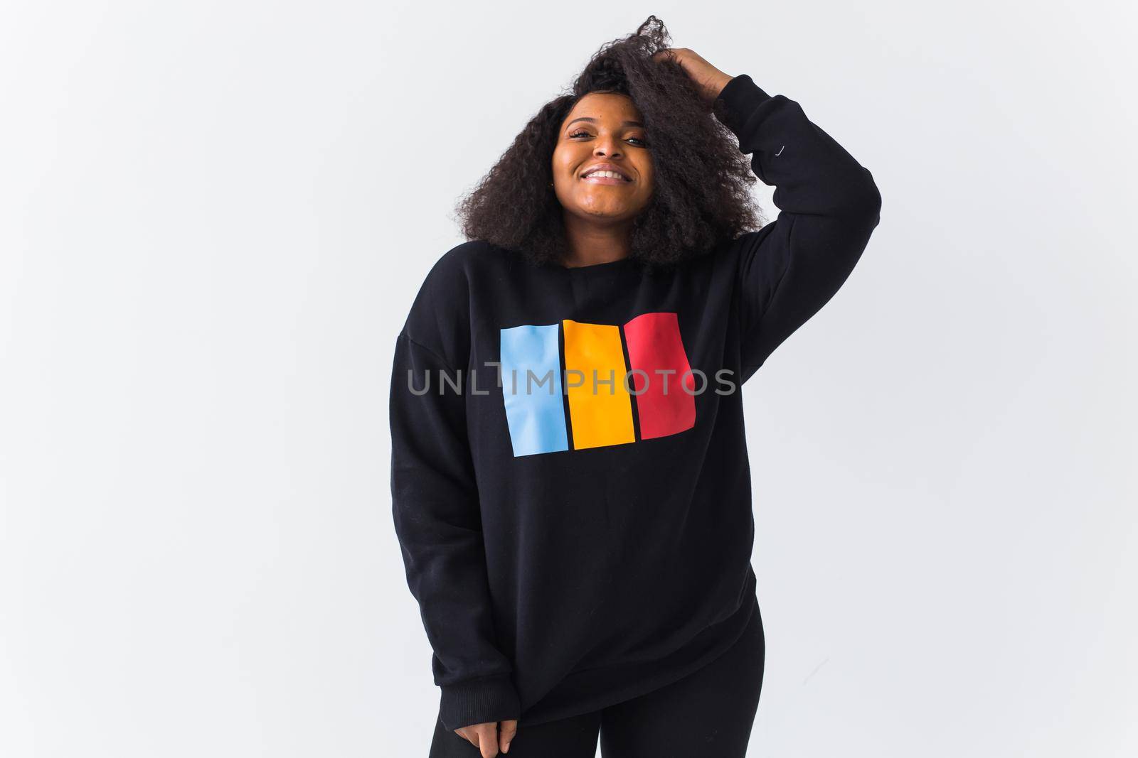 Beautiful African American woman posing in black hoodie on a white background. Fashion with afro hairstyle.