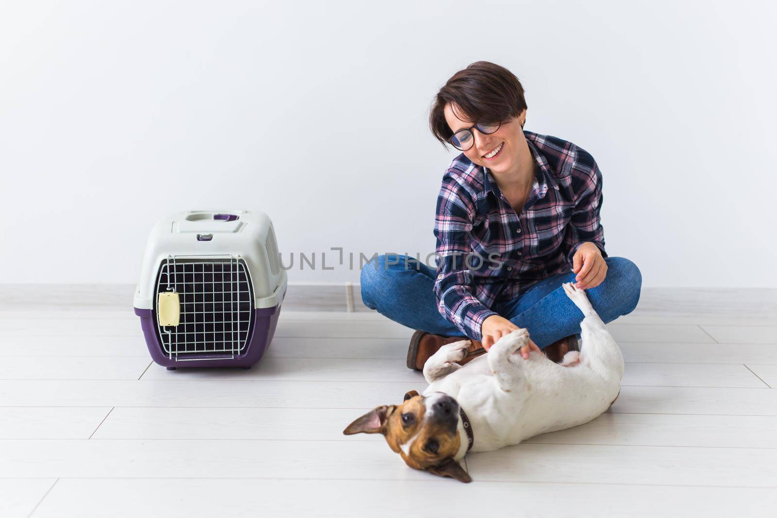 Dog carrying bags and pets owner concept - Attractive cheerful female in plaid shirt holds favourite pet. Happy woman with her jack russell terrier.