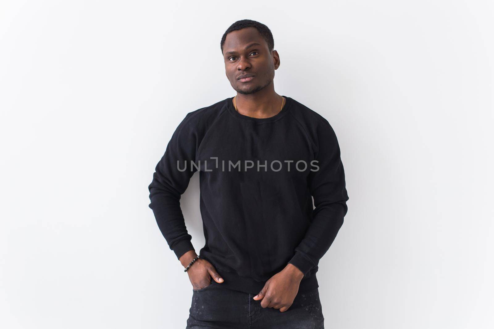 Portrait handsome young black man dressed in jeans and hoodie on white background. Street fashion and modern youth culture