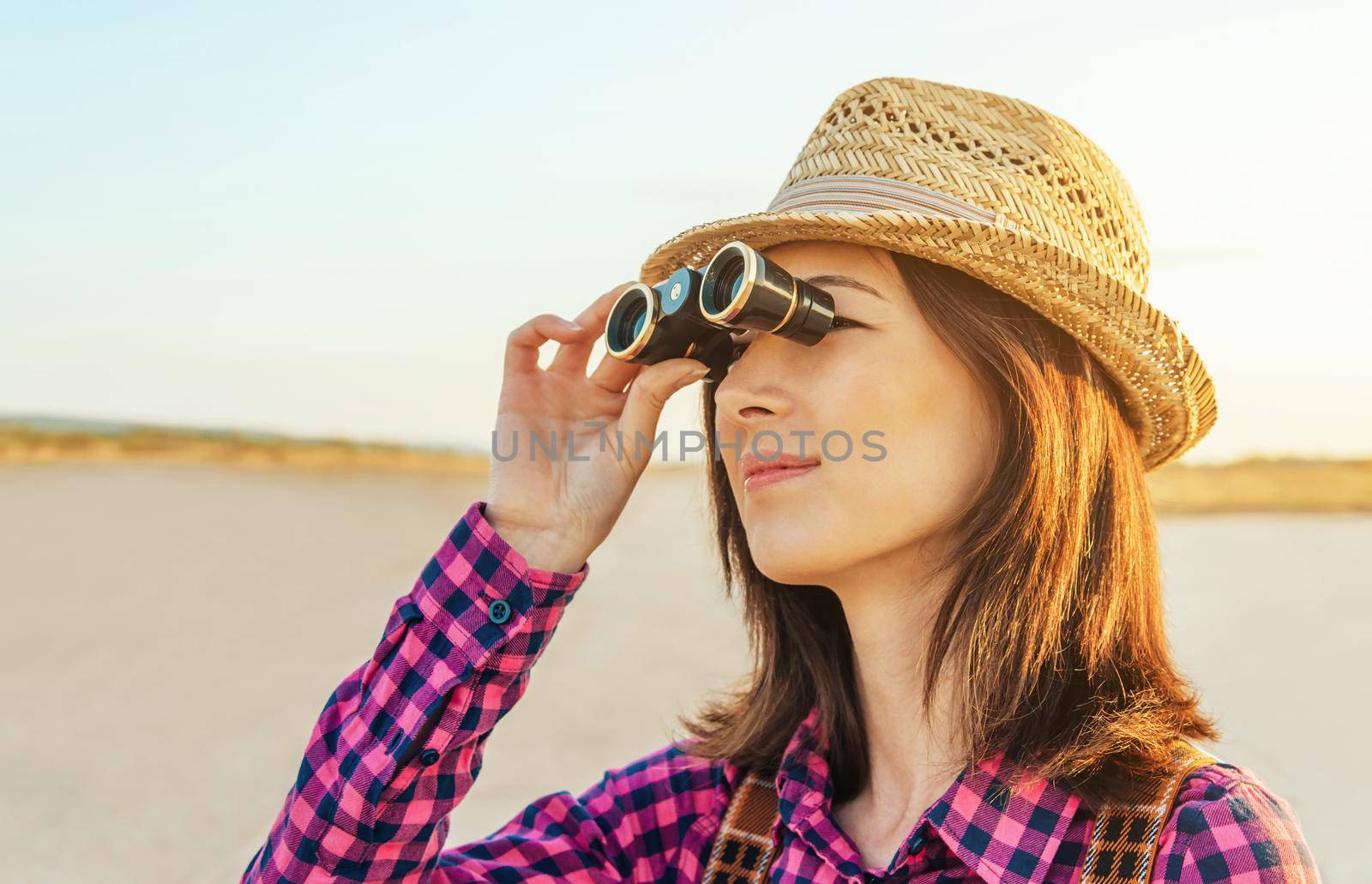 Beautiful young hipster girl looks through binoculars