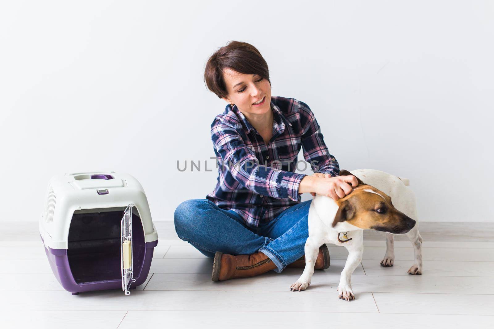 Dog carrying bags and pets owner concept - Attractive cheerful female in plaid shirt holds favourite pet. Happy woman with her jack russell terrier by Satura86