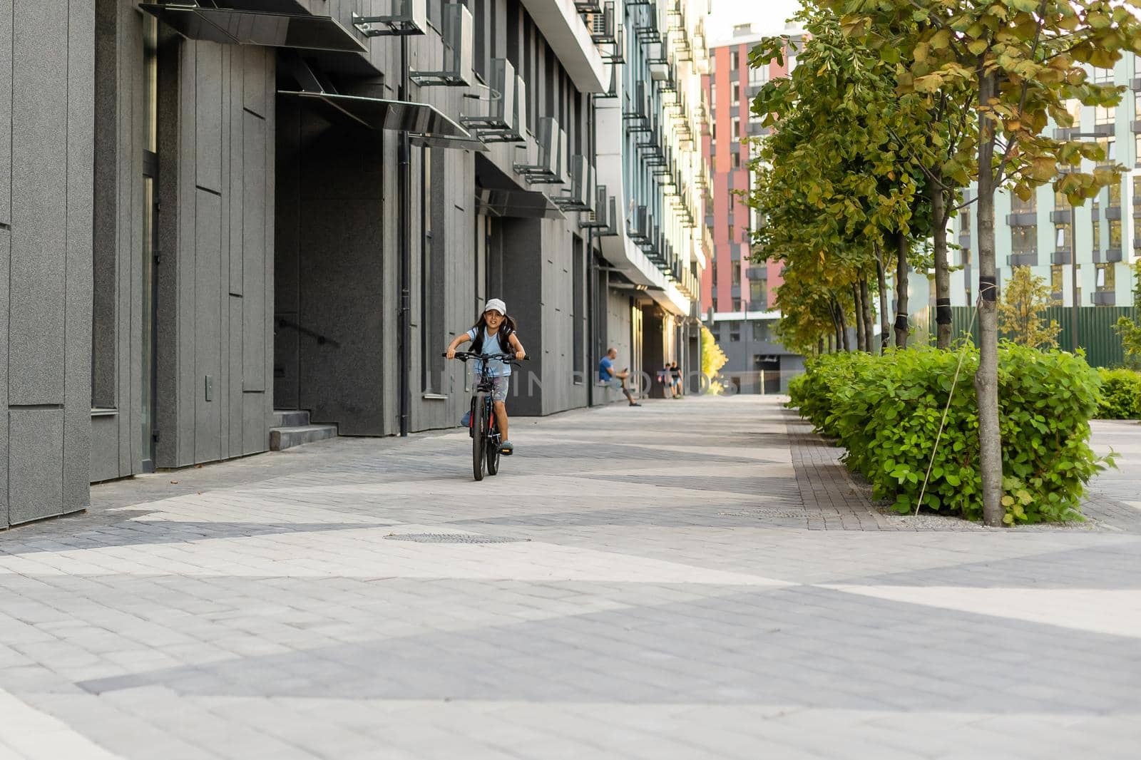 Happy little girl riding a bike in the city by Andelov13