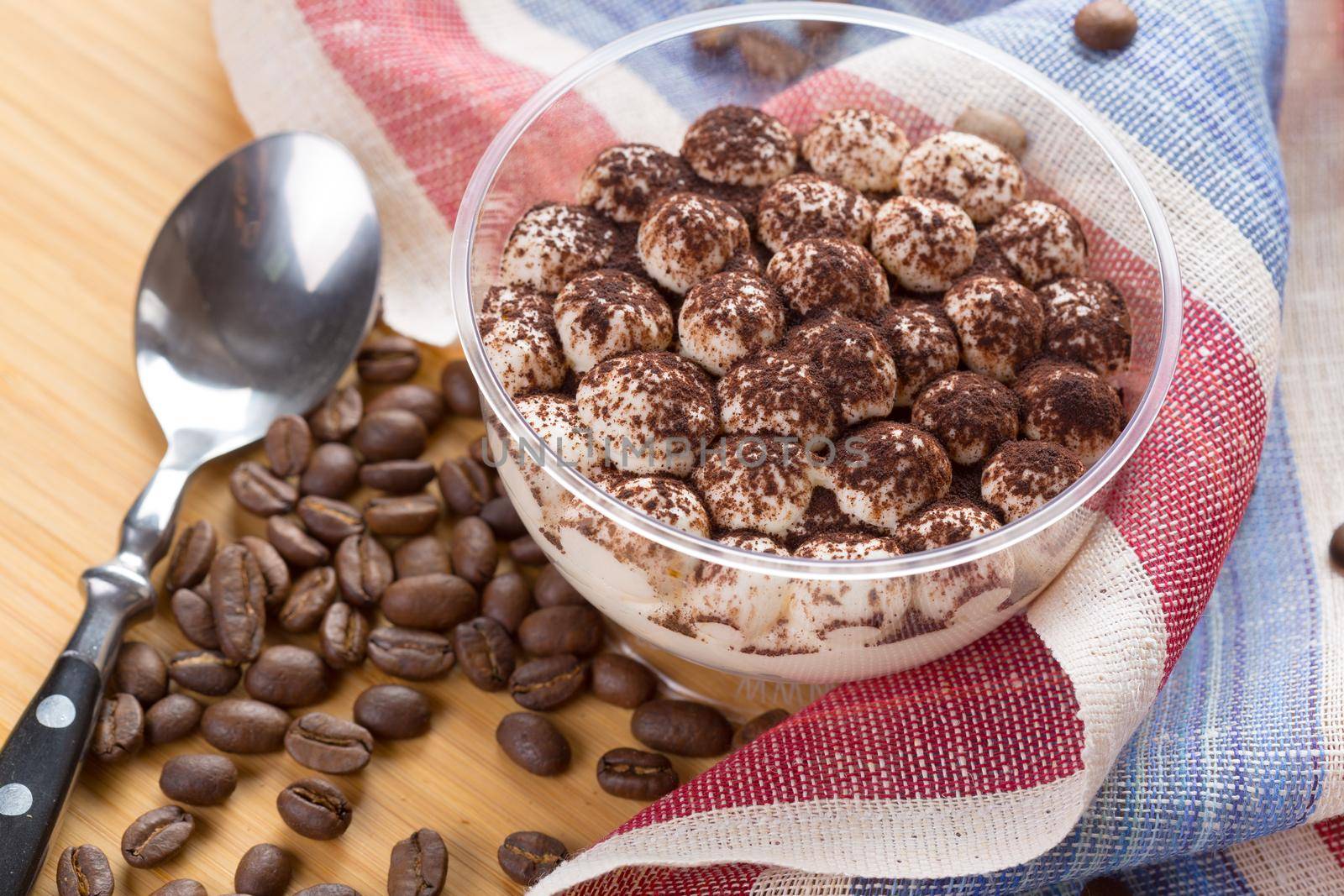 Tiramisu dessert in a glass cup on wooden table close up