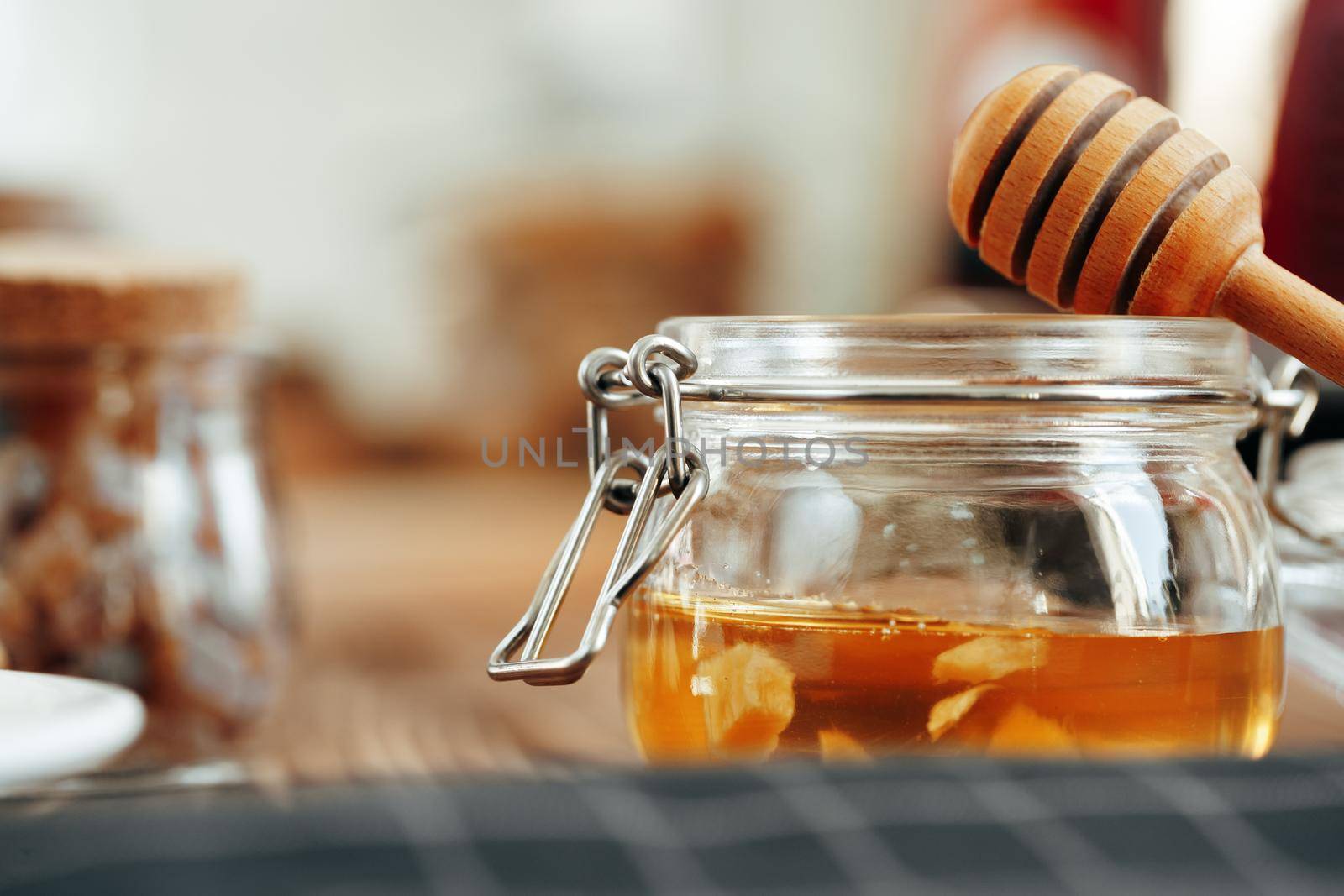 Glass jar of honey on wooden kitchen table, close up