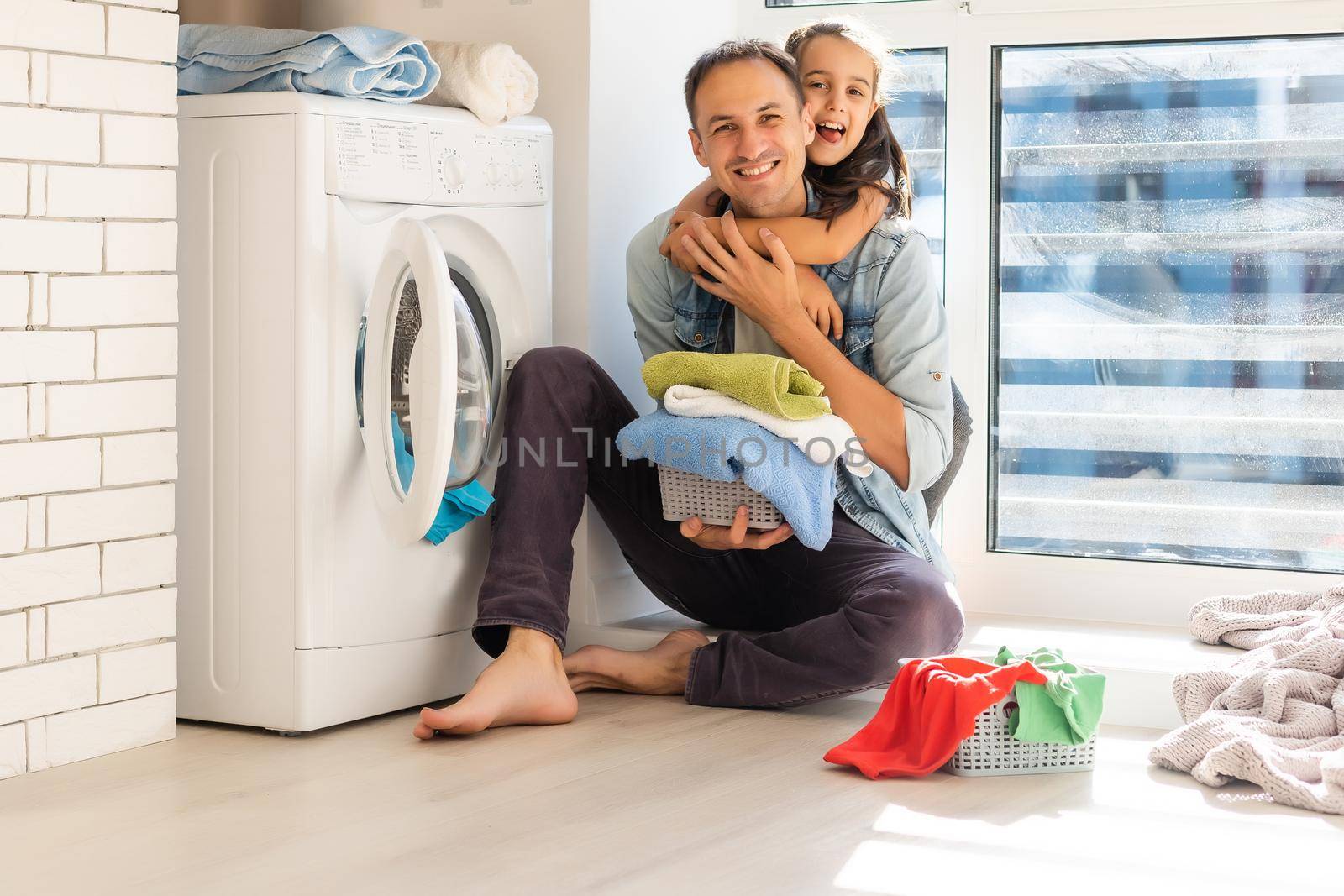 Happy Family loading clothes into washing machine in home by Andelov13