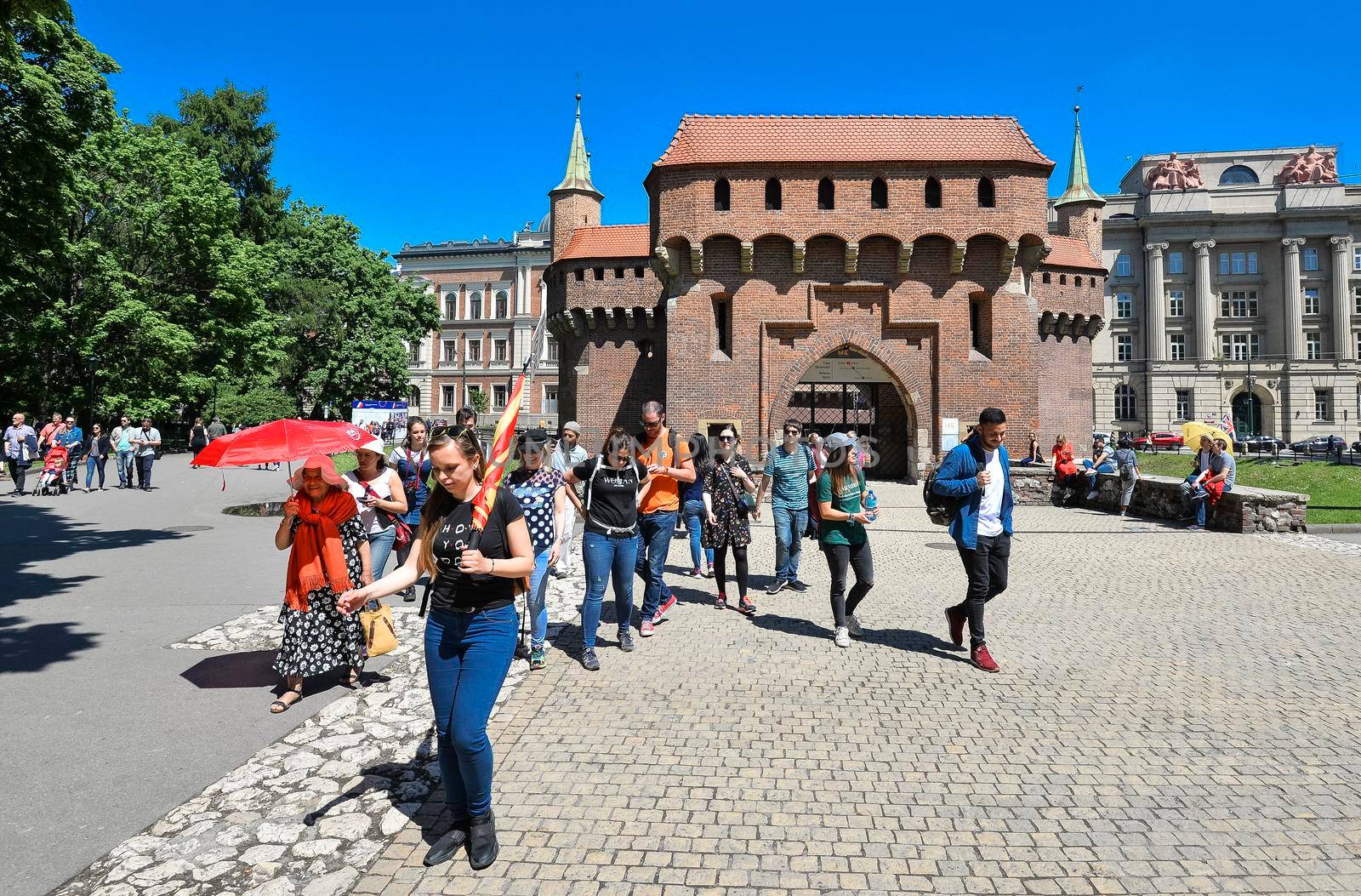 Krakow, Poland - May 20, 2019: The Krakow Barbican - a fortified outpost. It is a historic gateway leading into the Old Town of Krakow, Poland. Group of tourists on excursions near Krakow Barbican