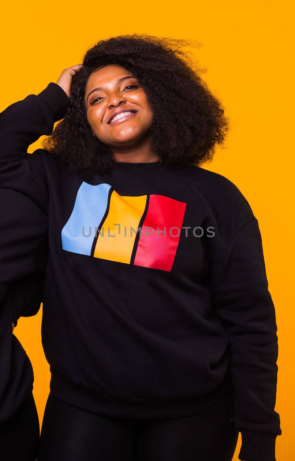 Young beautiful african american girl with an afro hairstyle. Portrait on yellow background