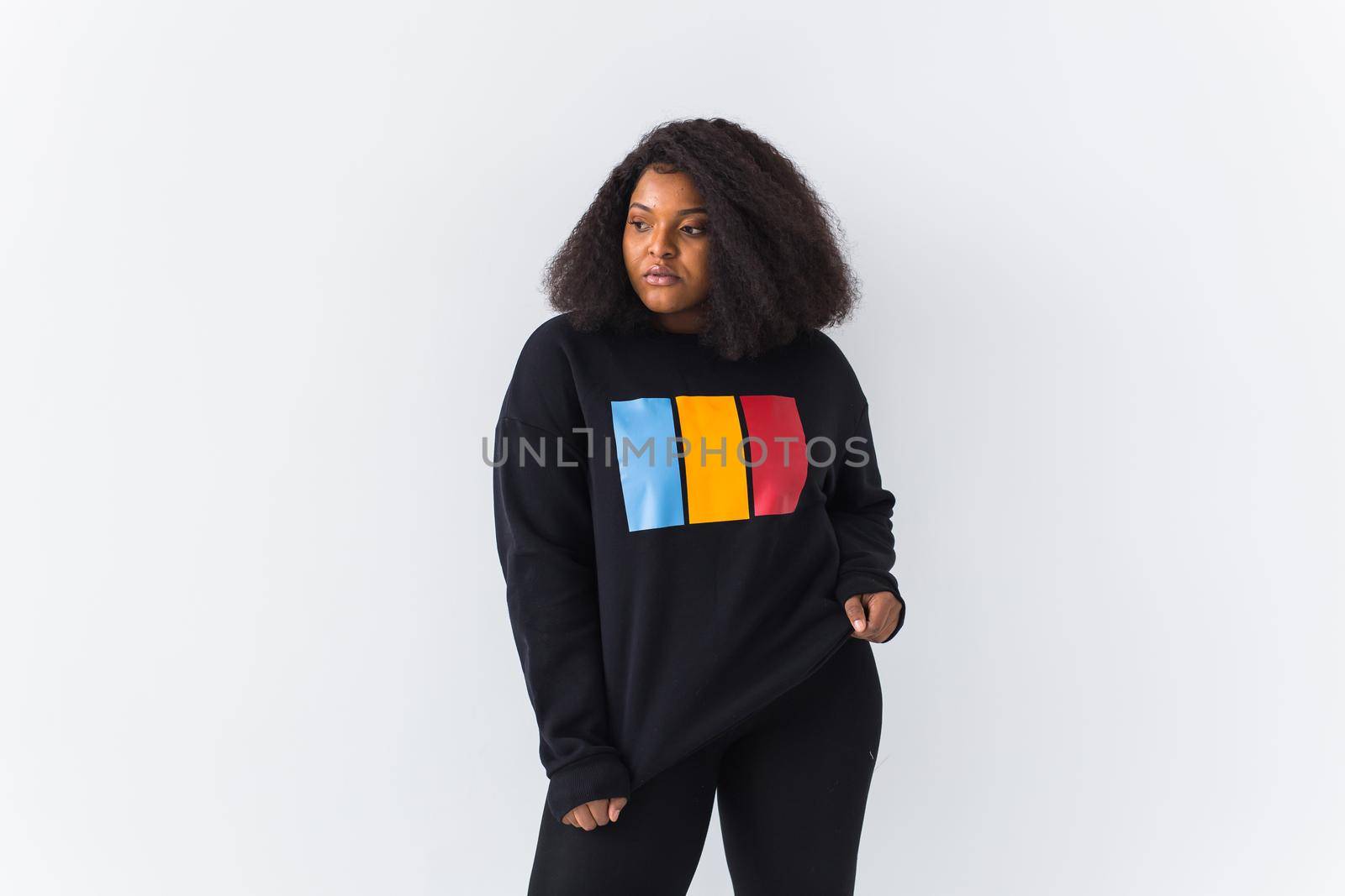 Beautiful African American woman posing in black hoodie on a white background. Fashion with afro hairstyle.