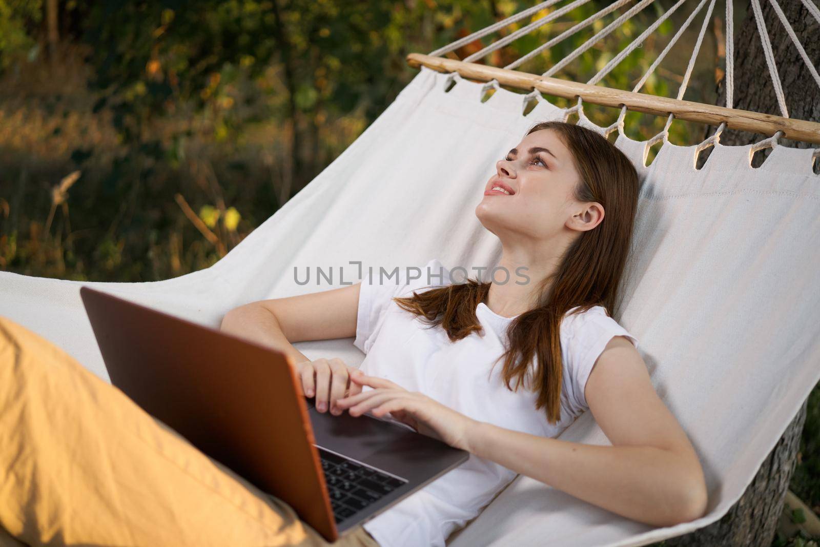 woman working on laptop in nature hammock freelance. High quality photo