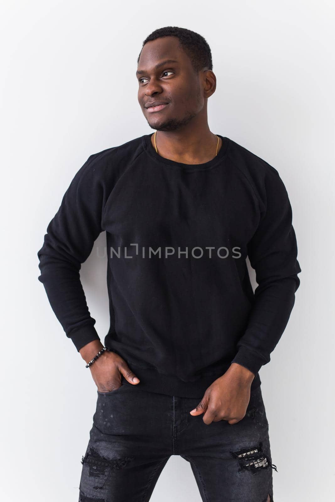Handsome African American man posing in black sweatshirt on a white background. Youth street fashion photo with afro hairstyle. by Satura86