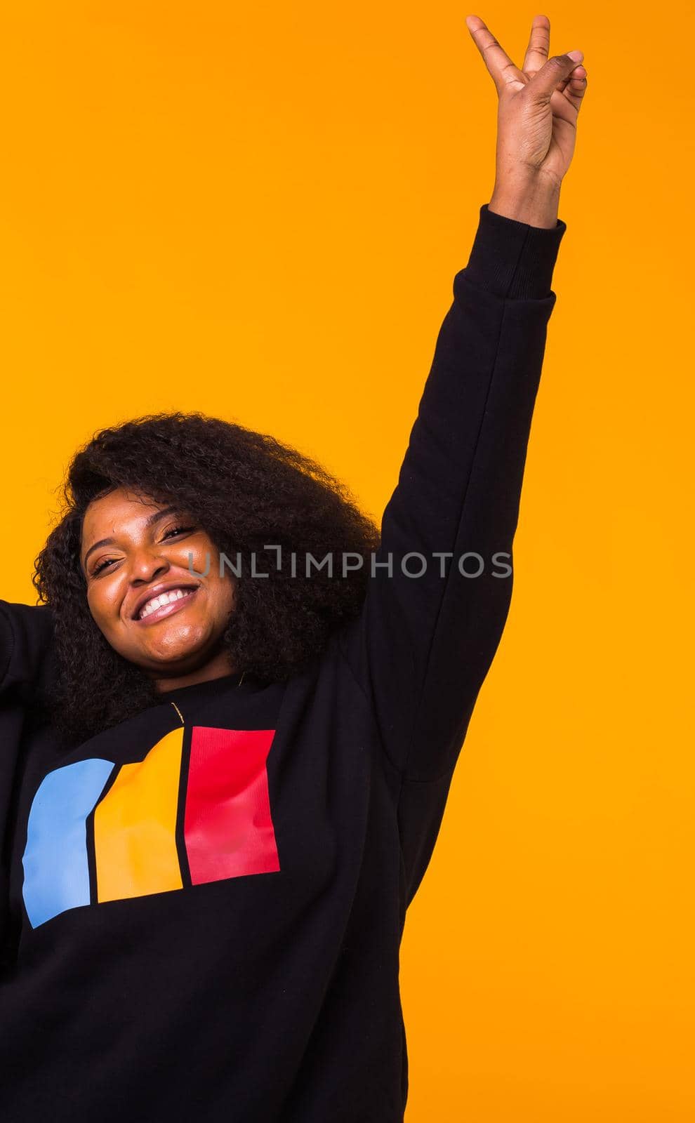 Young beautiful african american girl with an afro hairstyle. Portrait on yellow background. by Satura86