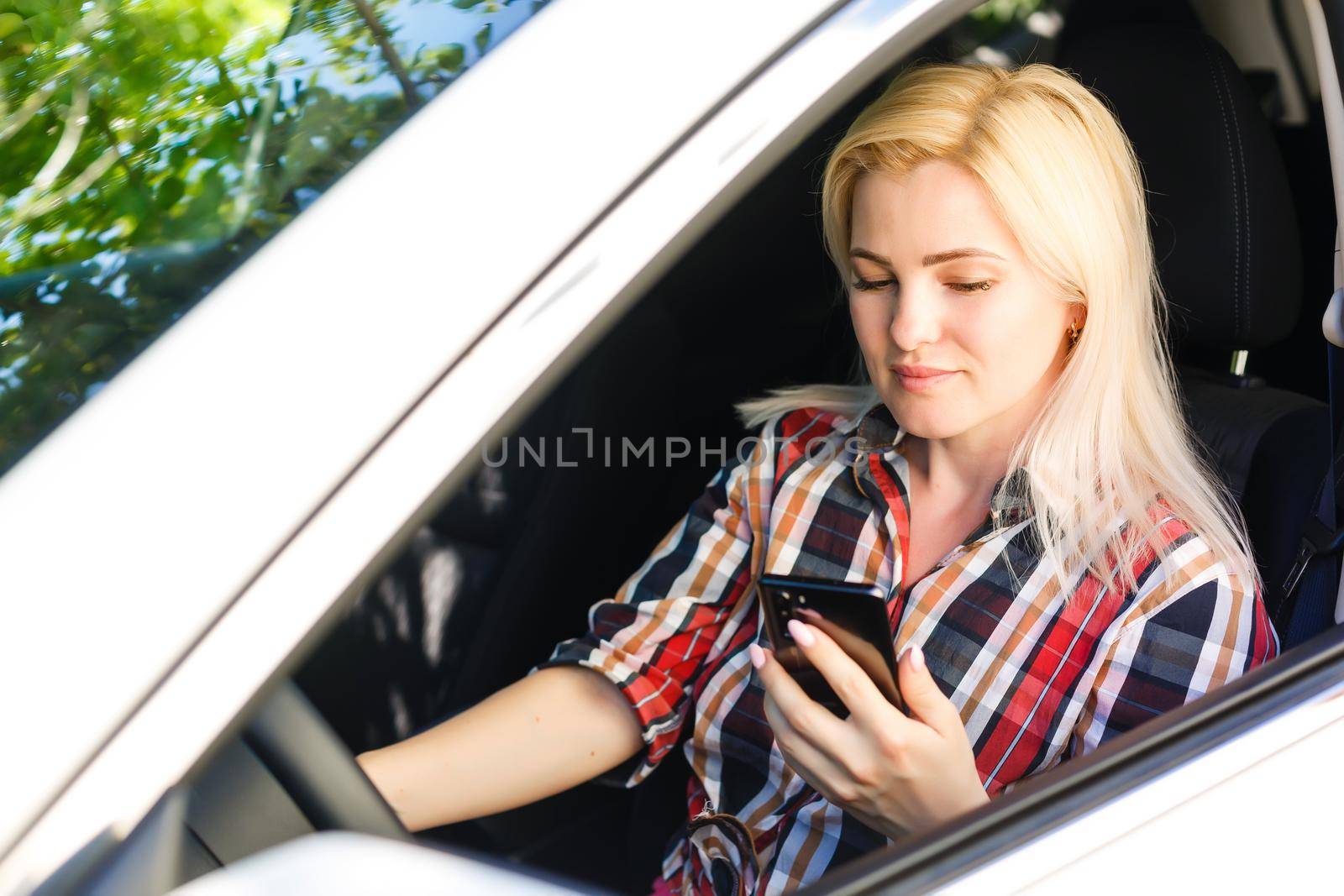 Young woman looks at her smartphone in a car. by Andelov13