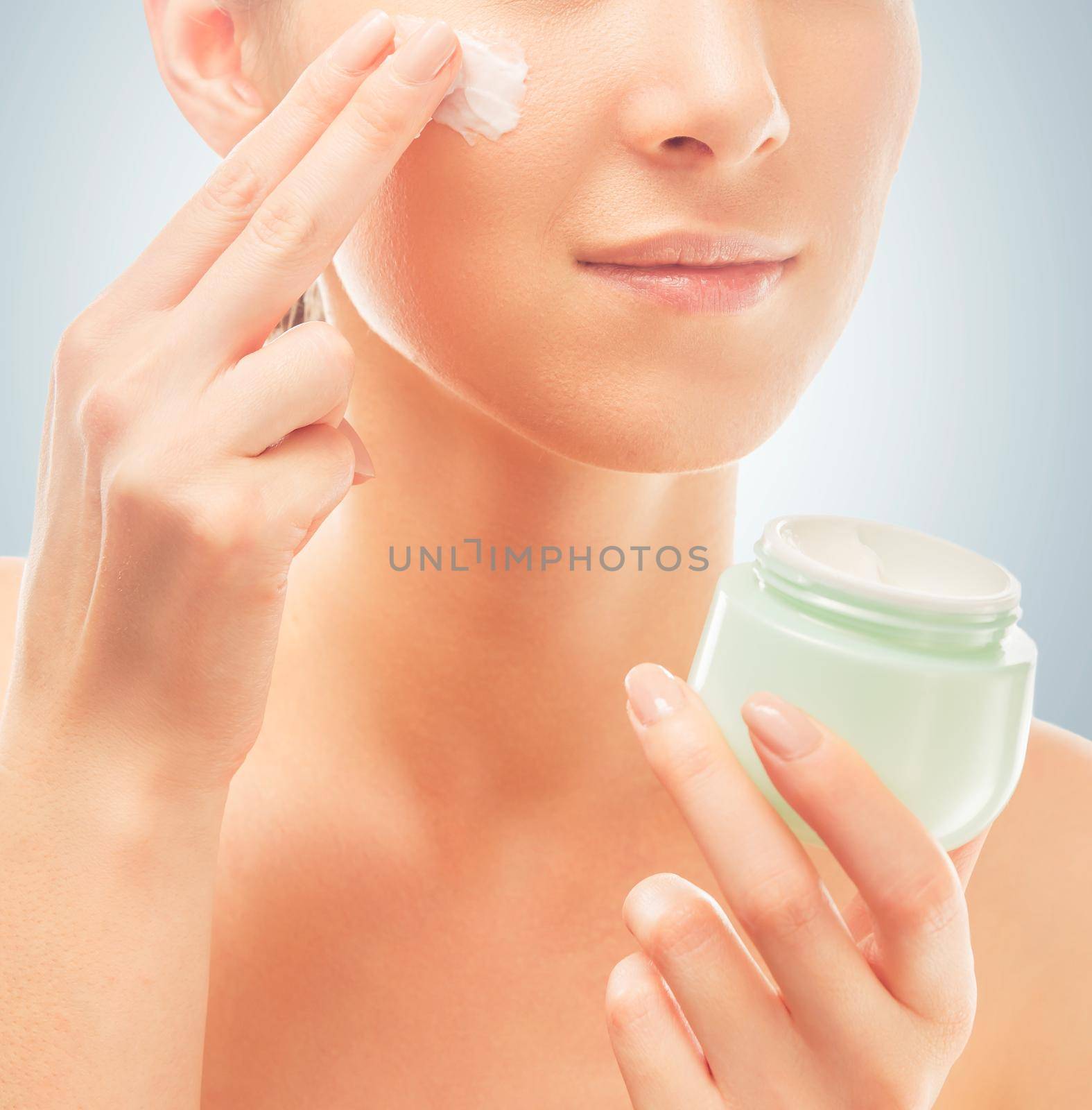 Woman applies cream on face, close-up by alexAleksei