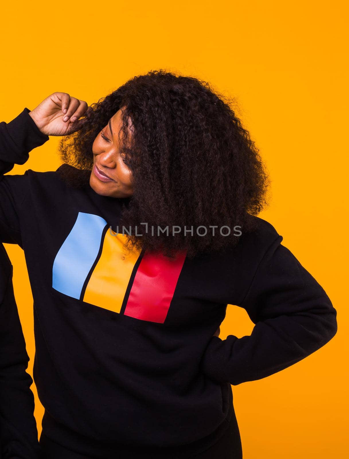 Young beautiful african american girl with an afro hairstyle. Portrait on yellow background