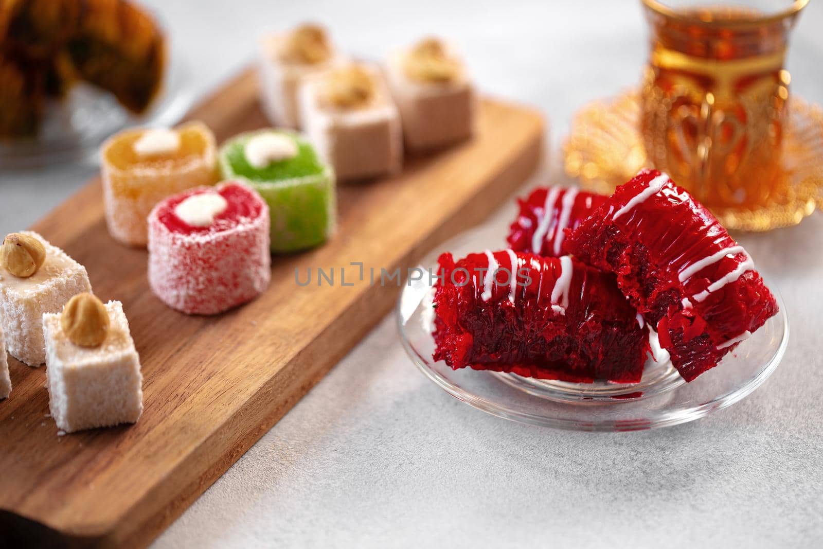 Various Turkish sweets and cup of tea on white textured background, close up