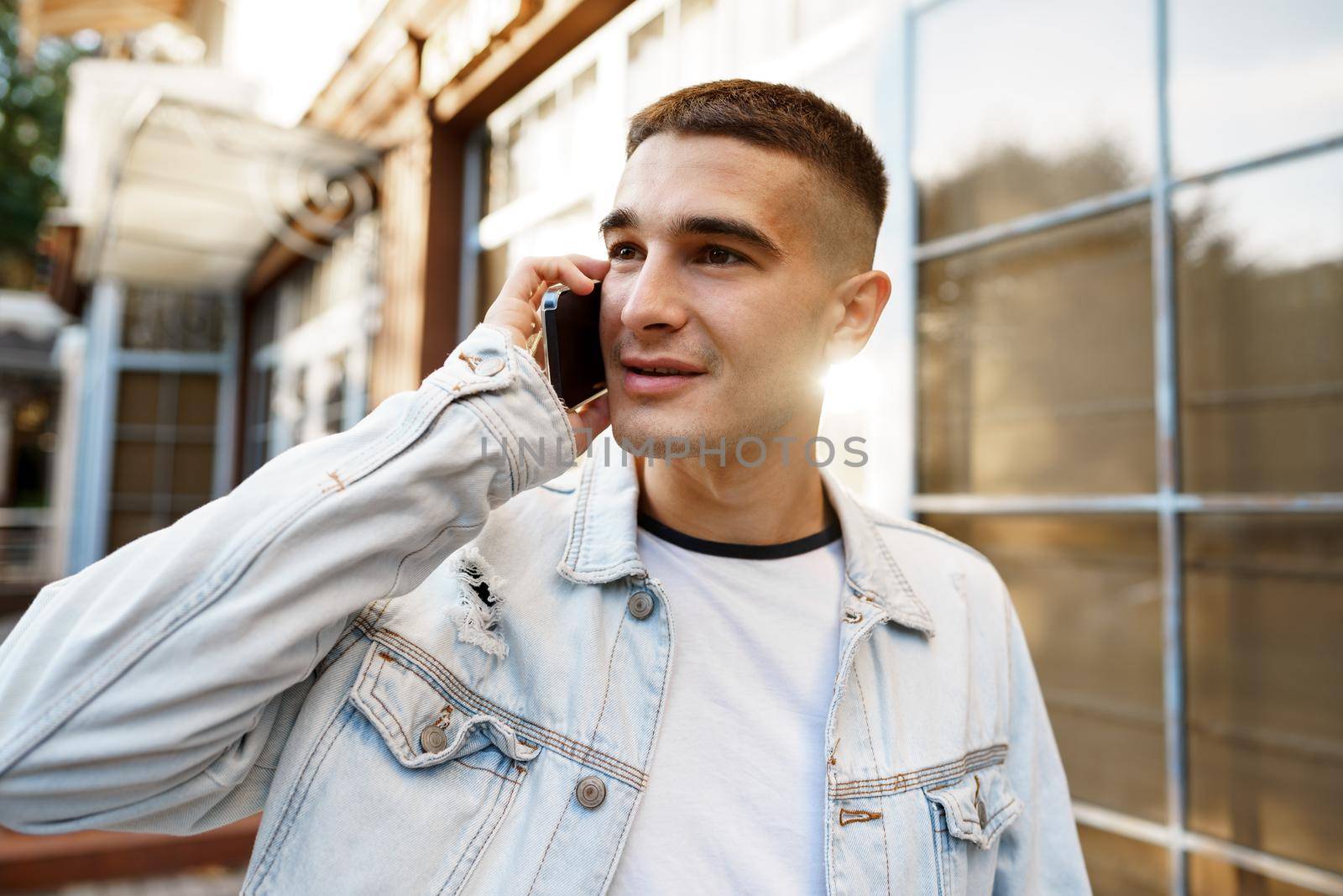 Young casual man walking on the city street and talking on the phone, close up portrait