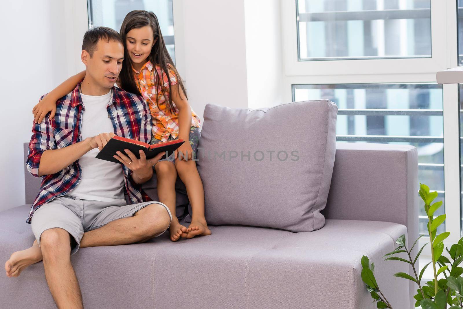 a young father with his little daughter reads the Bible by Andelov13