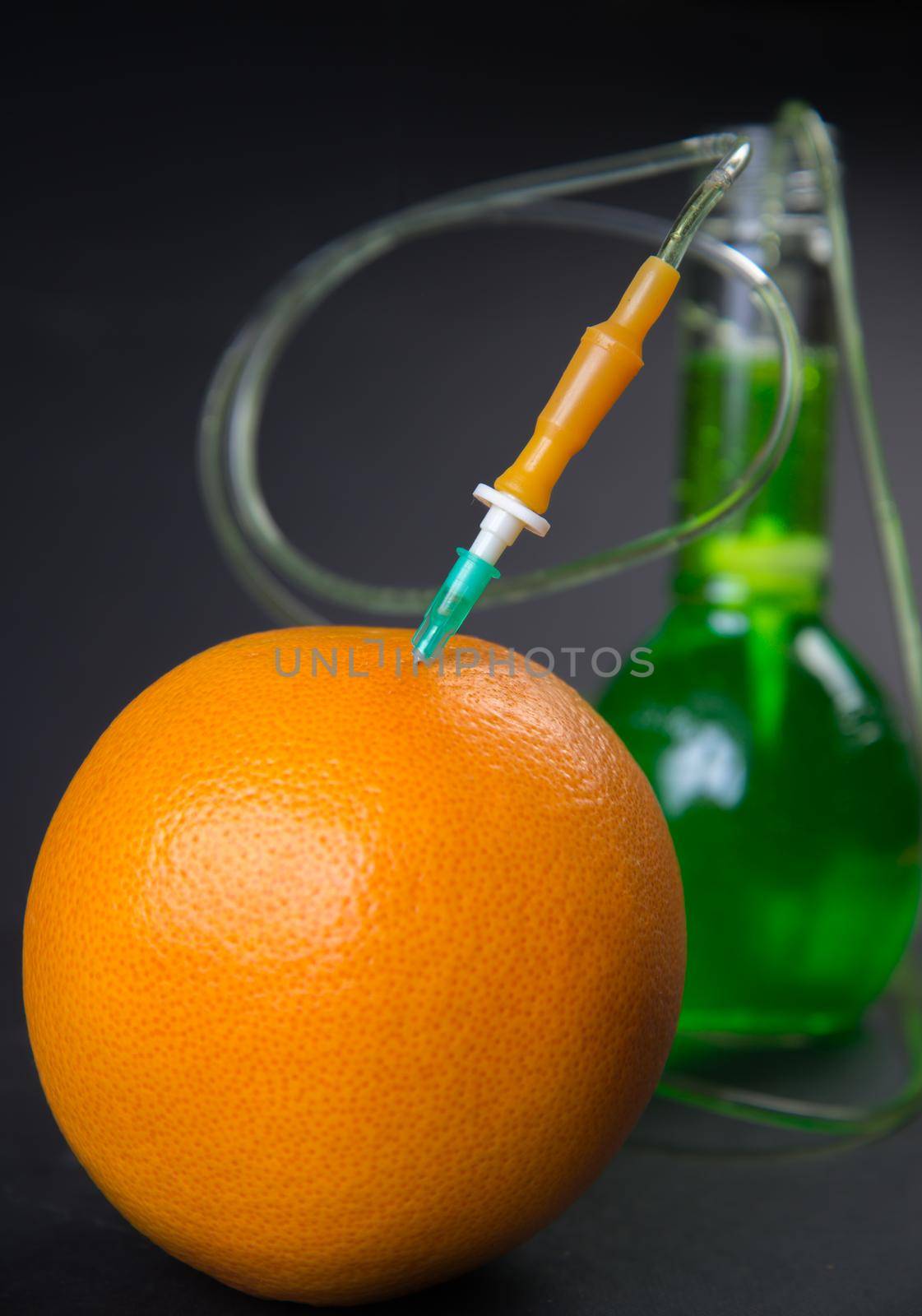 Green liquid in the drop counter injected into grapefruit on a black background