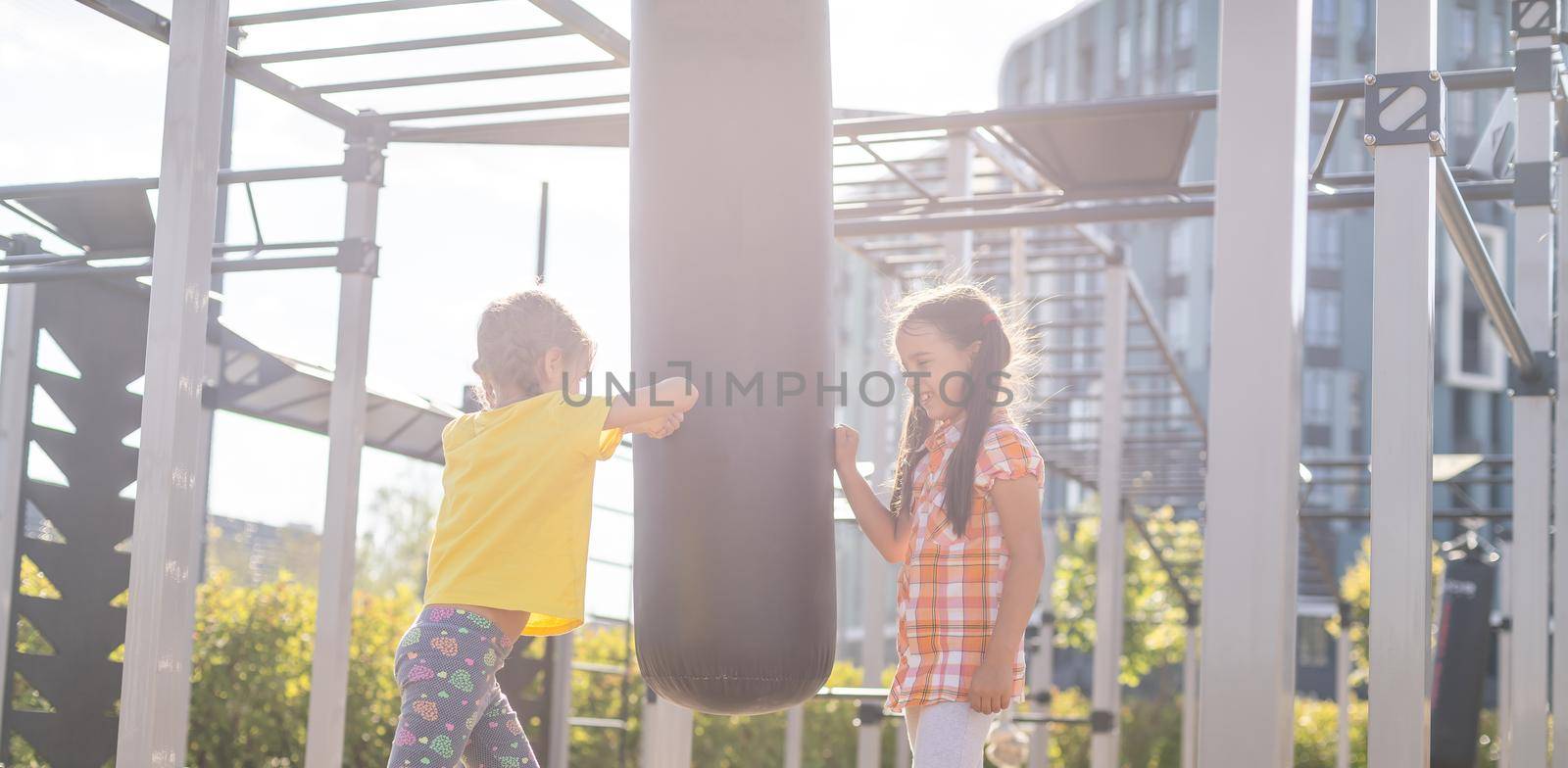 Two cute little girls having fun on a playground outdoors in summer. Sport activities for kids. by Andelov13