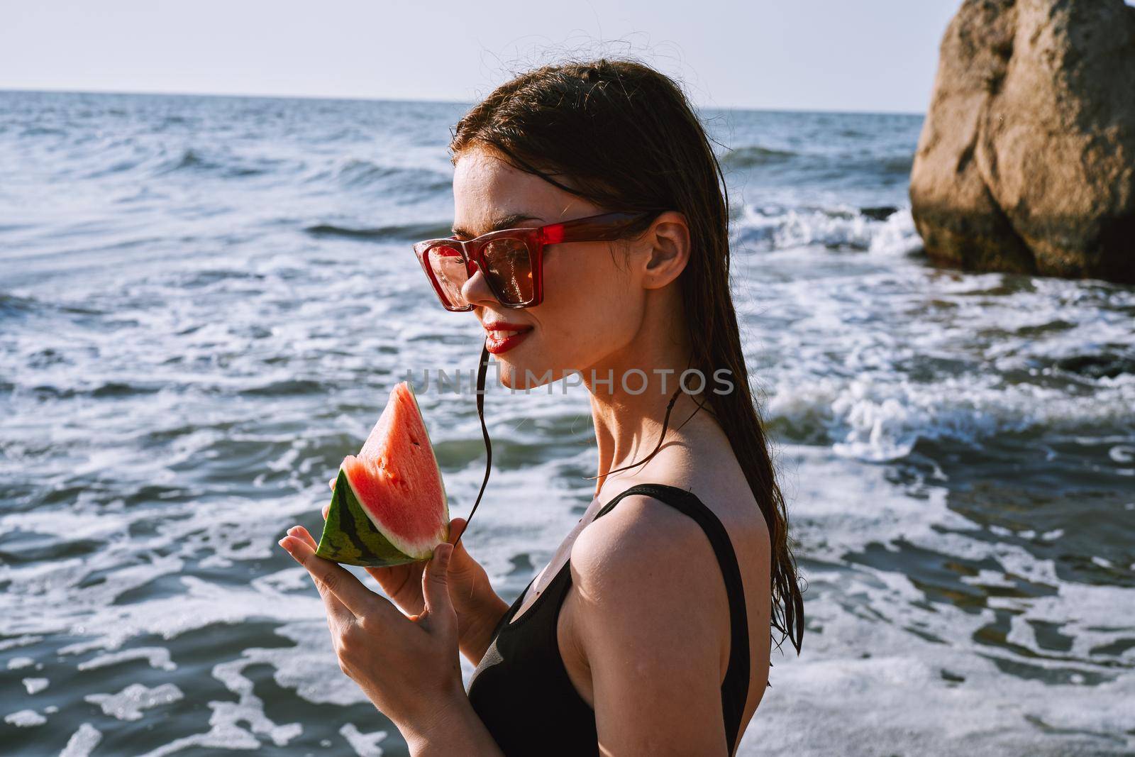 woman in black swimsuit with watermelon by the ocean. High quality photo