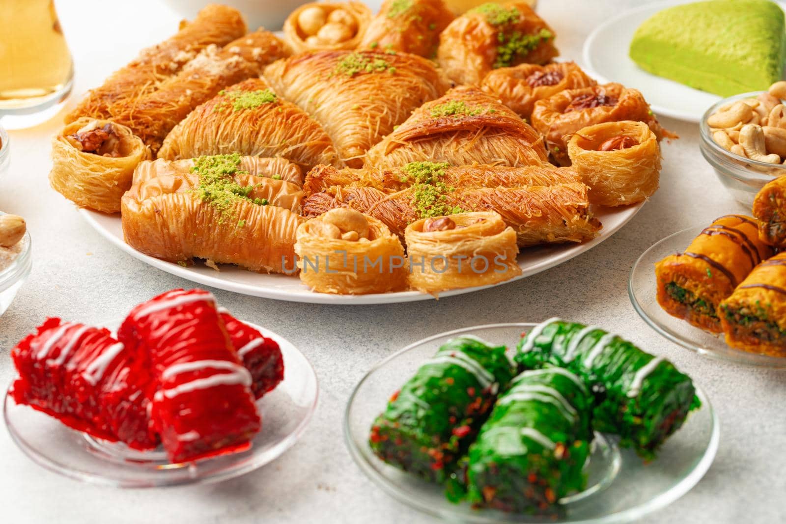 Various Turkish sweets and cup of tea on white textured background, close up
