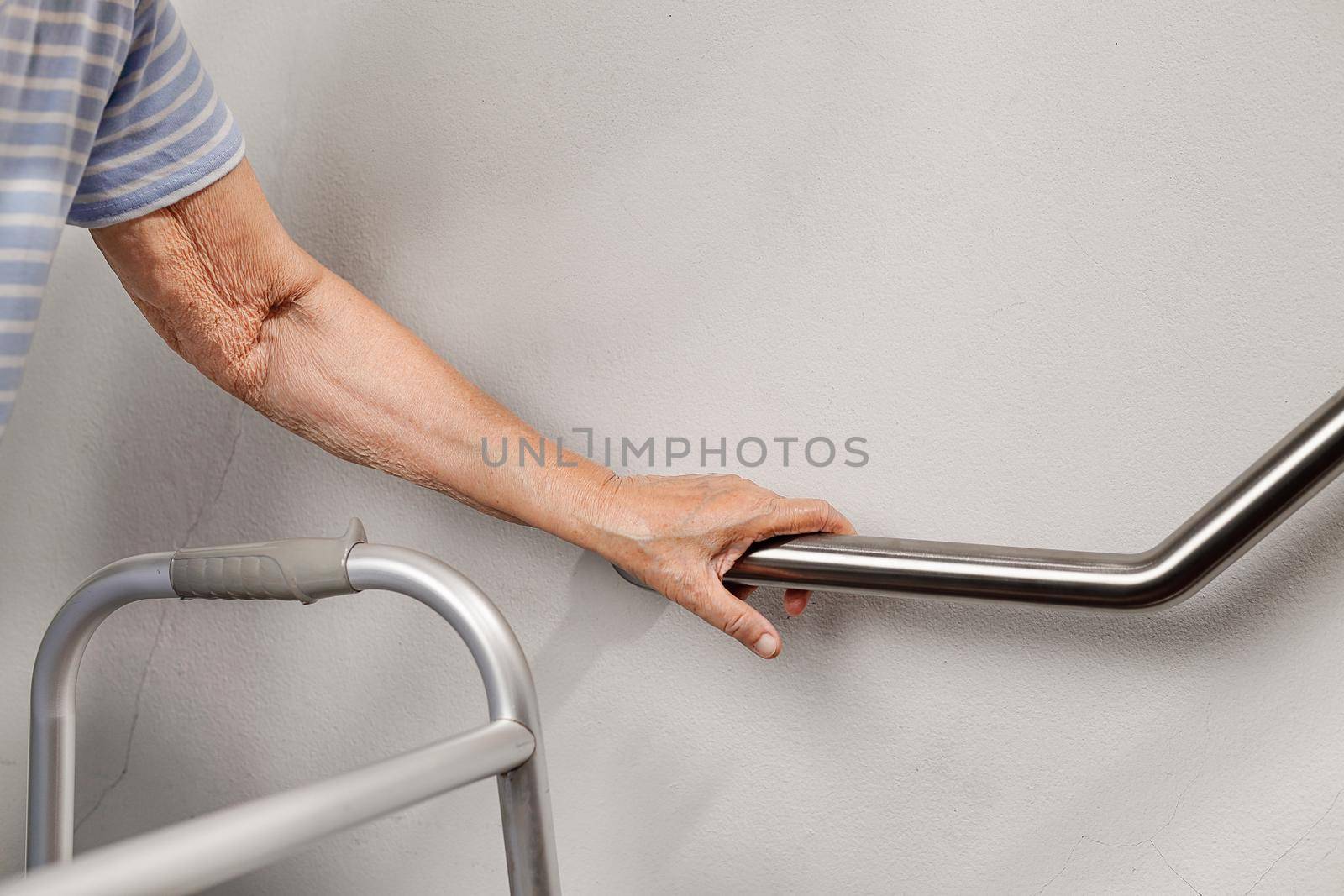 Elderly woman holding on handrail for safety walk steps