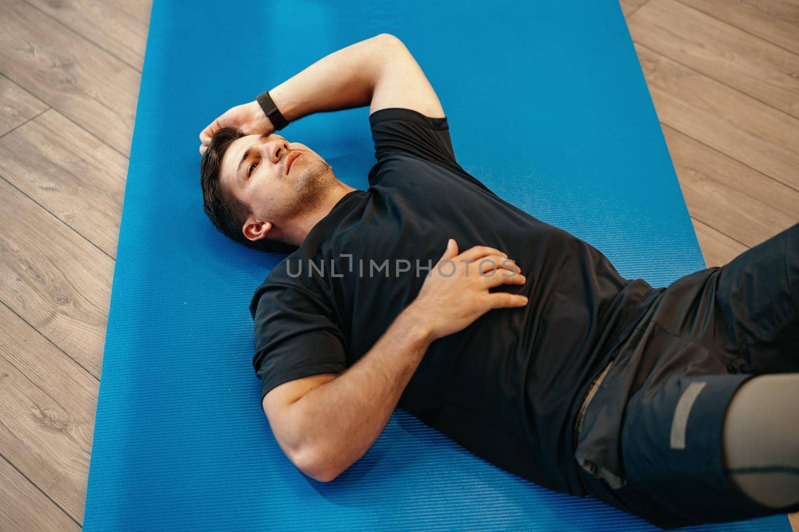 Young muscular caucasian handsome man doing abs exercises on a mat