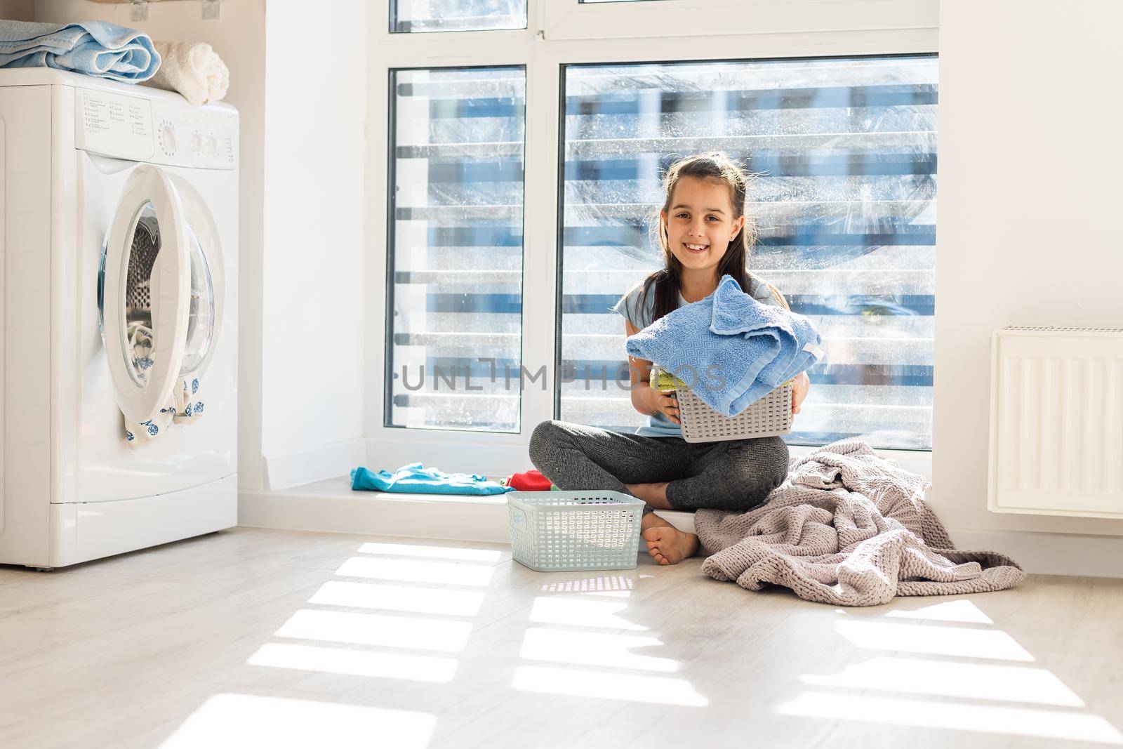 Happy little girl doing laundry in home interior by Andelov13