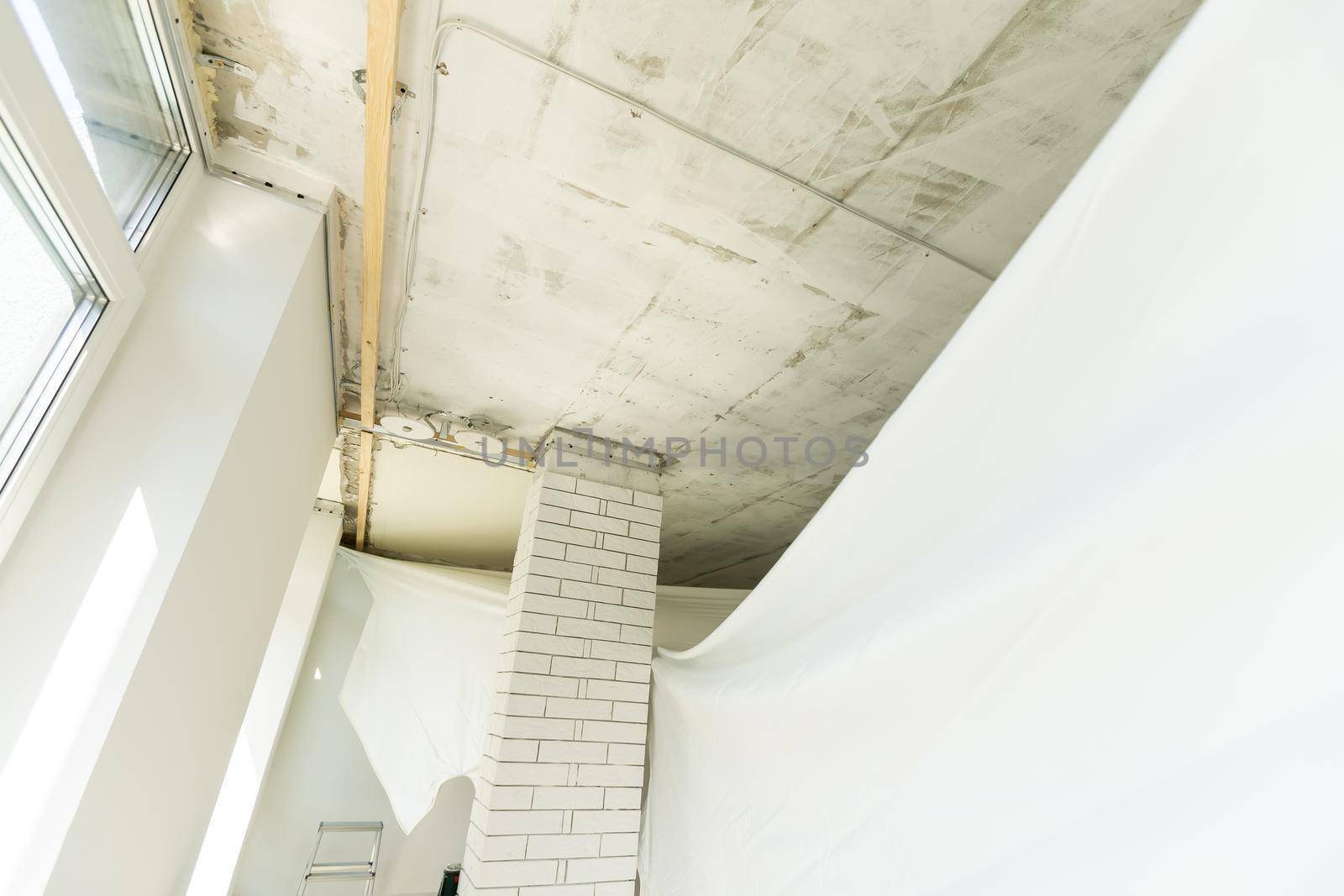 repairmen install stretch ceiling made of pvc vinyl film using a gas heat gun