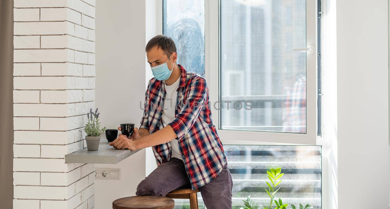 man with face mask serving coffee through window, shop open after lockdown.