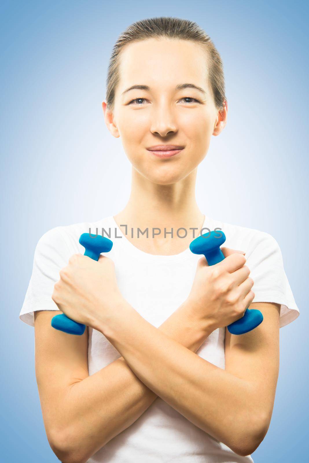 Young happy woman is holding dumbbells, arms crossed