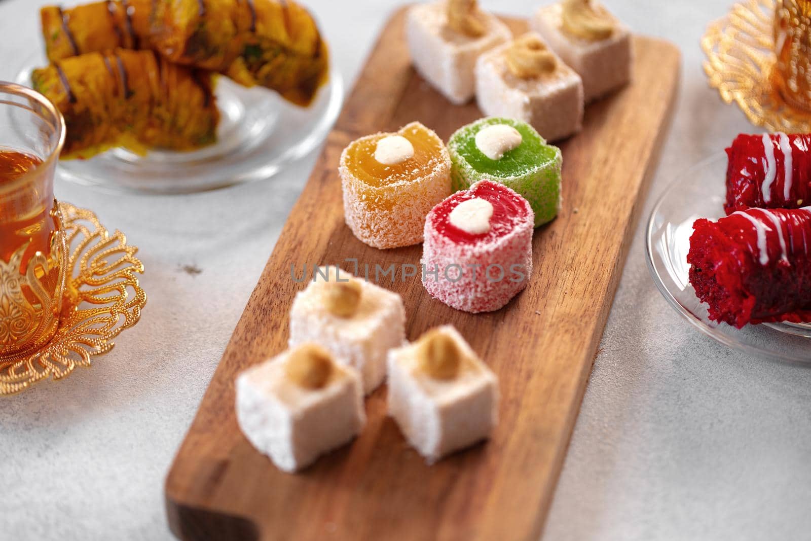 Various Turkish sweets and cup of tea on white textured background, close up