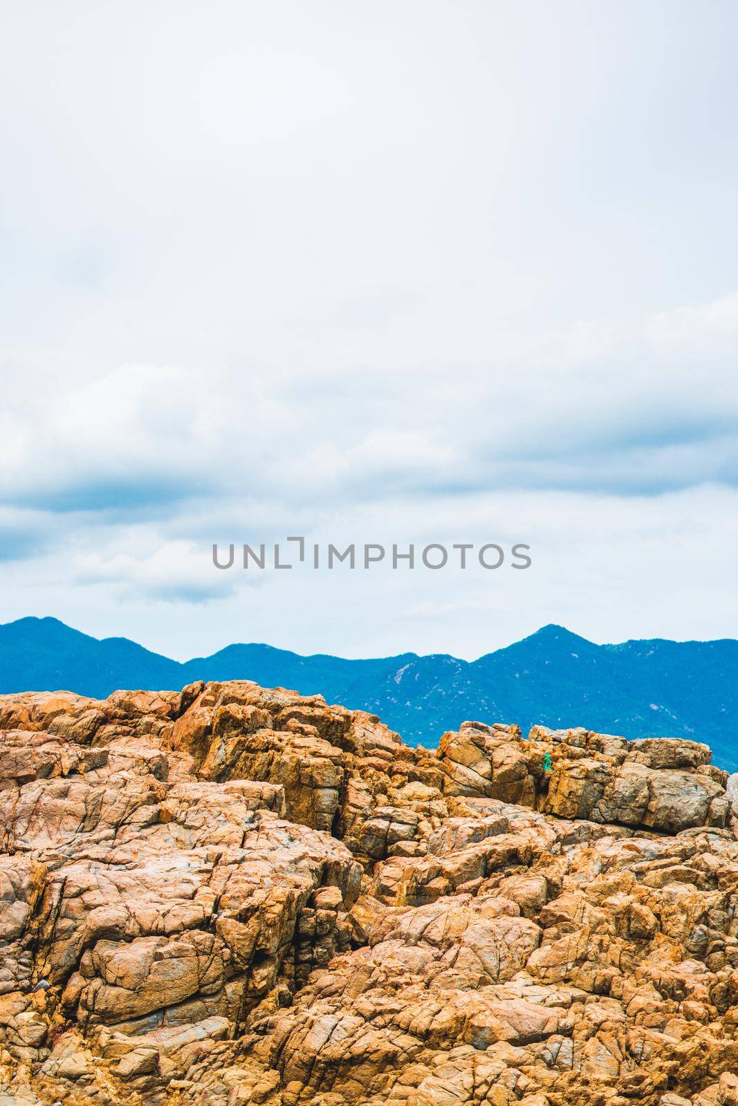 Beautiful natural composition, vivid orange brown yellow stone rock shabby cliff cracks, cumulus cloud sky, mountain background. Vacation after pandemic, beauty nature power. Vertical stories format.