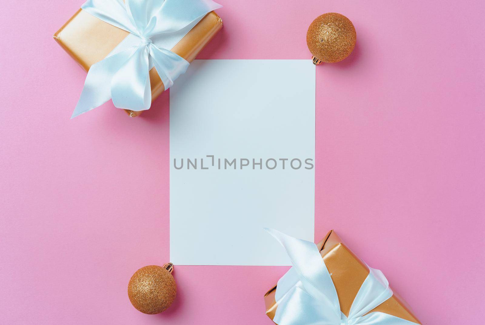 Christmas festive mock up with blank page, wrapped gifts and baubles on pink background