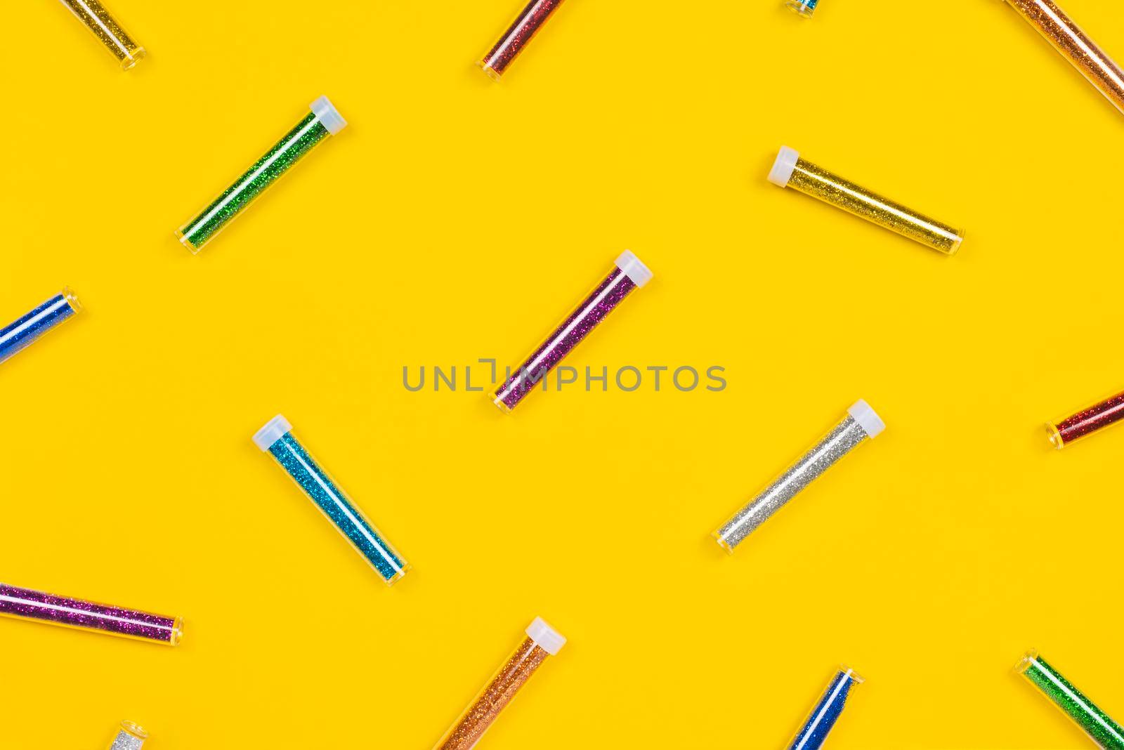 Jars of colorful glitter isolated on yellow background. Flat lay pattern. Glitter for craft or make-up concept