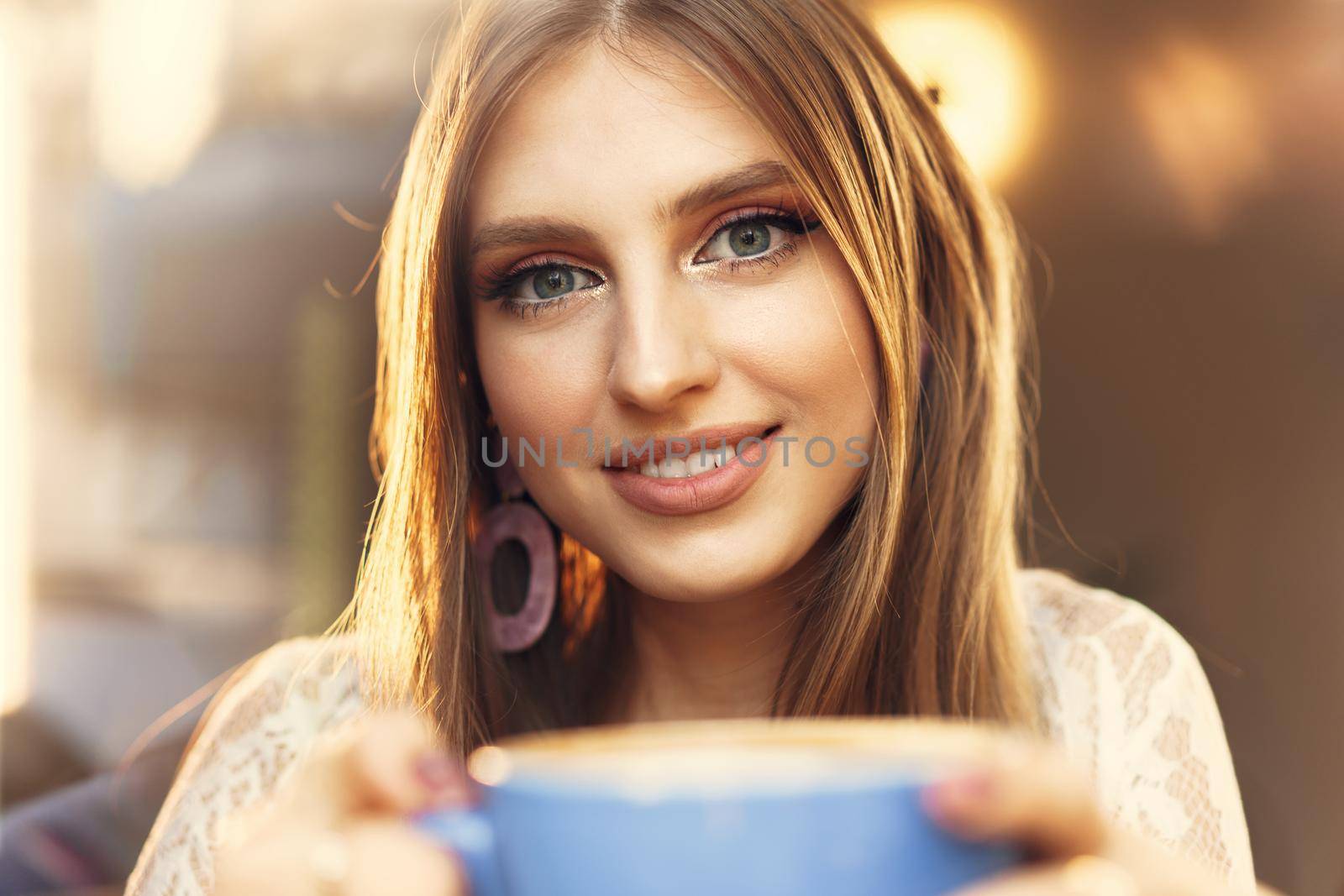 Portrait of a young woman having a cup of coffee and looking through the window. Close up.