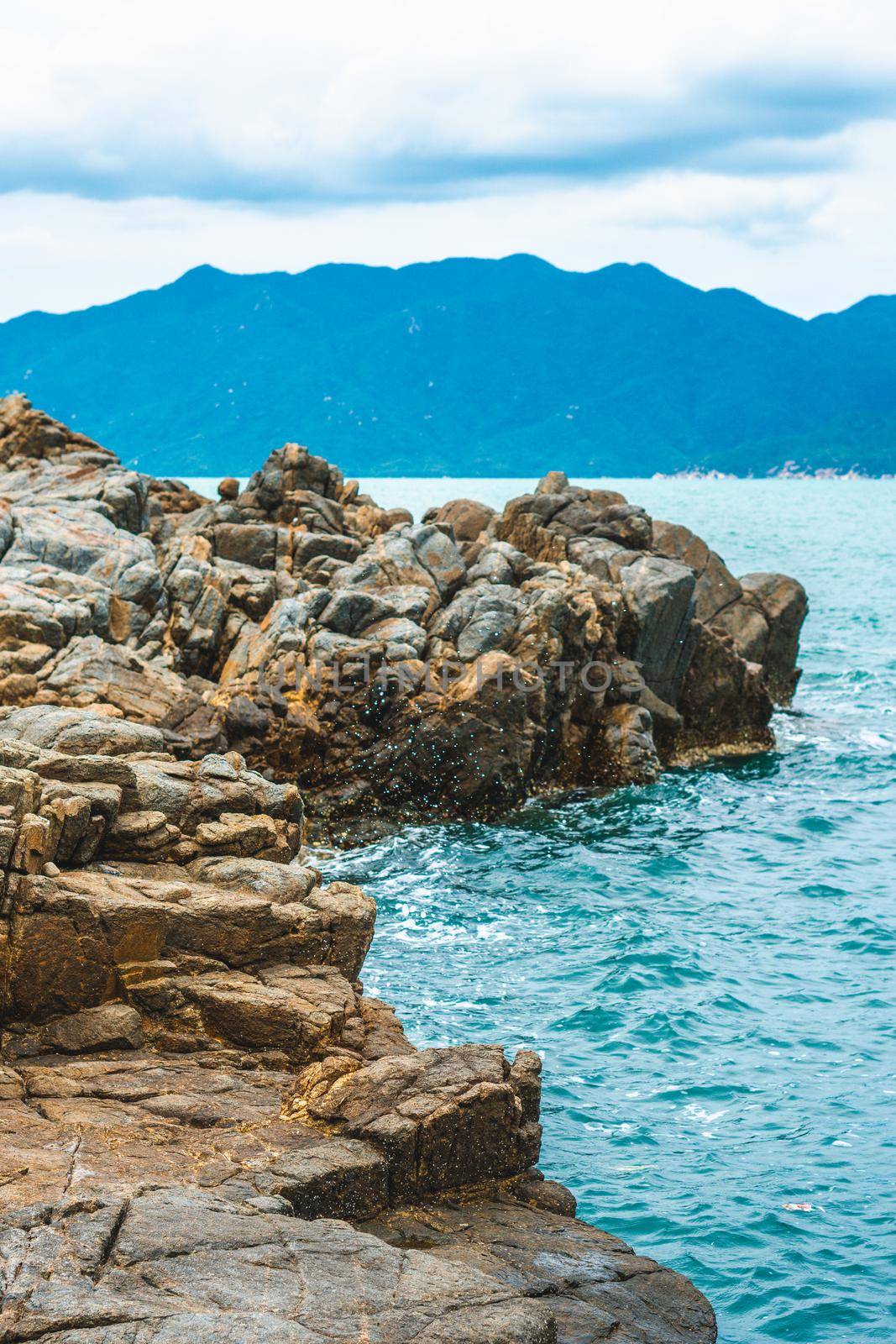 Beauty panorama pure blue lazure empty sea skyline, vivid brown gray rock shabby cliff, water splash, cumulus cloud sky, mountain island background. Concept sea tourism after pandemic, power in nature.