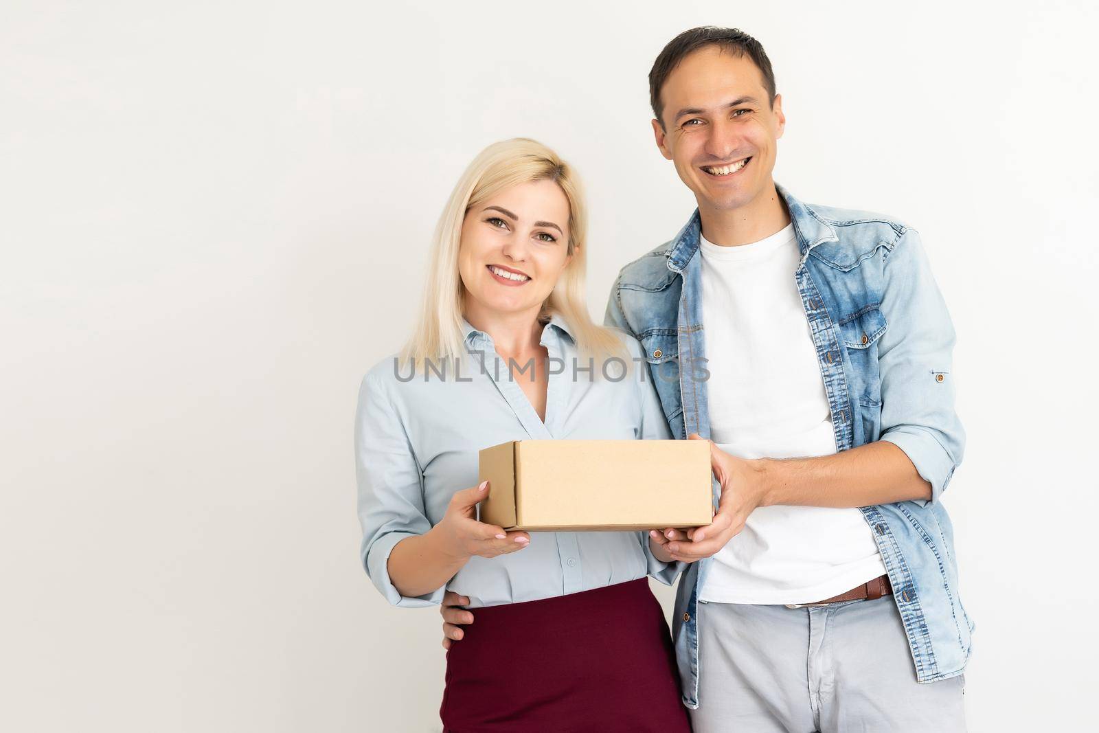 people, delivery, shipping and postal service concept - happy couple opening cardboard box or parcel at home by Andelov13