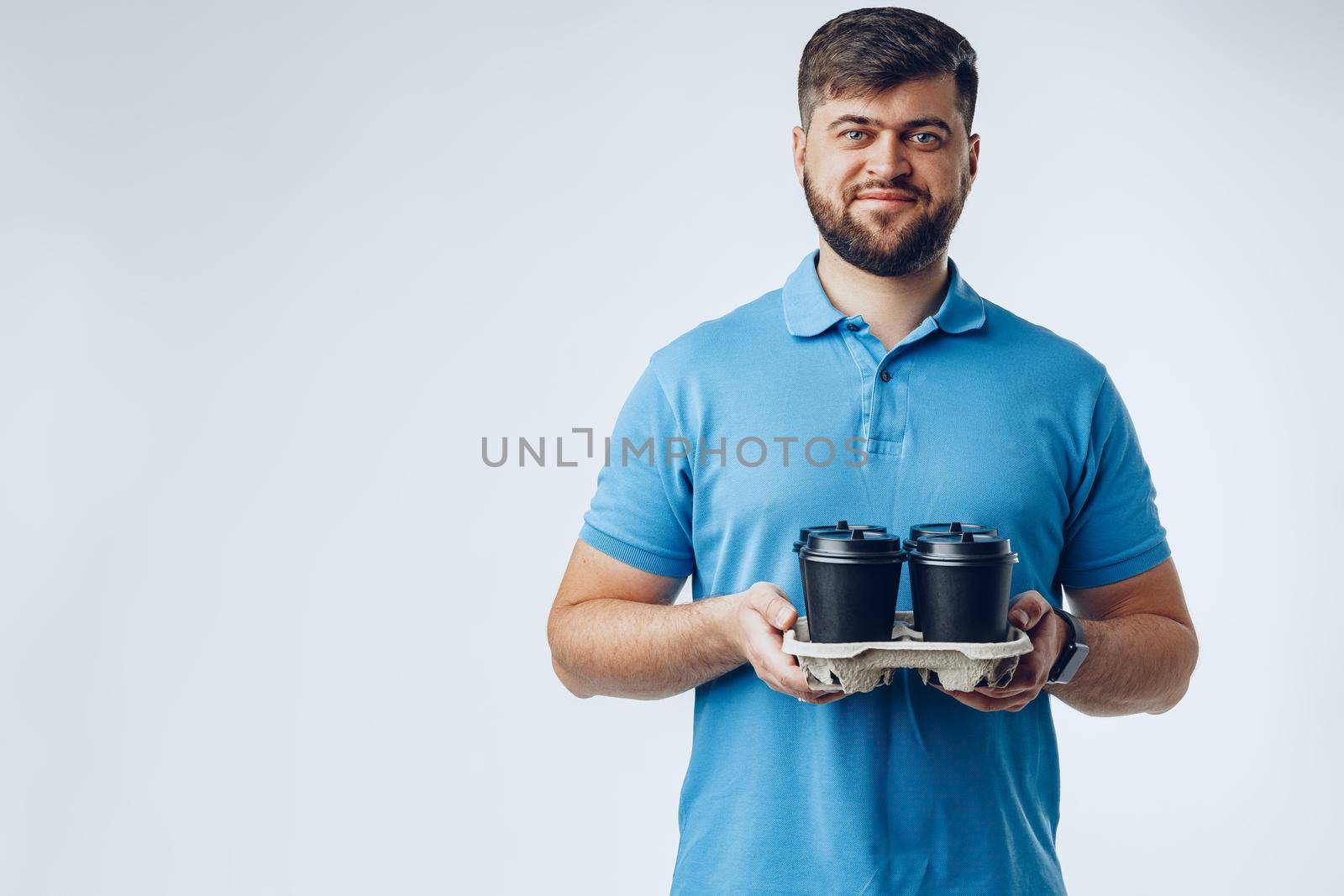 Man coffee shop worker giving takeaway cups of coffee on light grey background