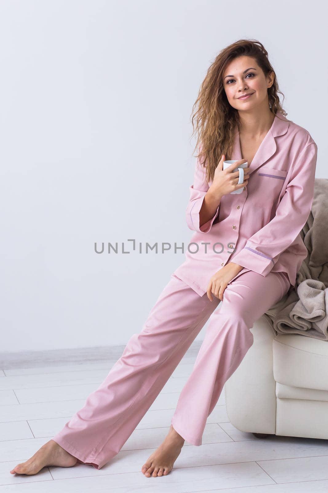 Young attractive woman dressed in beautiful colorful pajama posing as a model in her living room. Comfortable sleepwear, home relaxation and female fashion concept