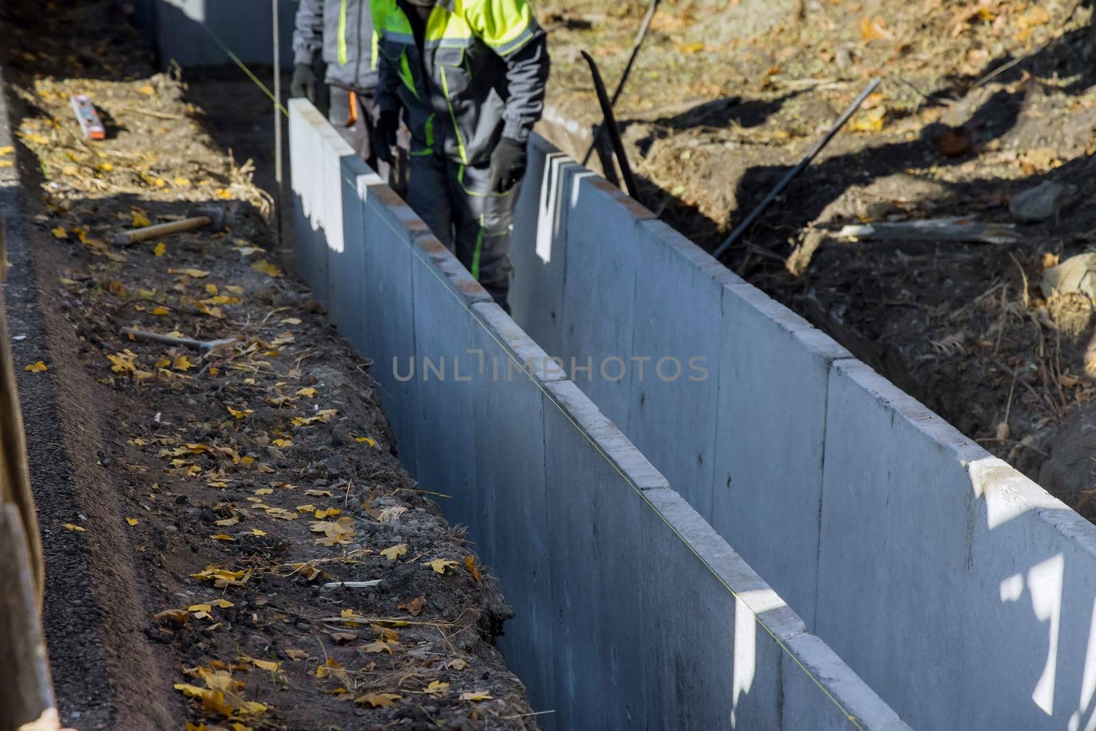 Construction road workers installing precast u-shape concrete drain at the reconstruction road