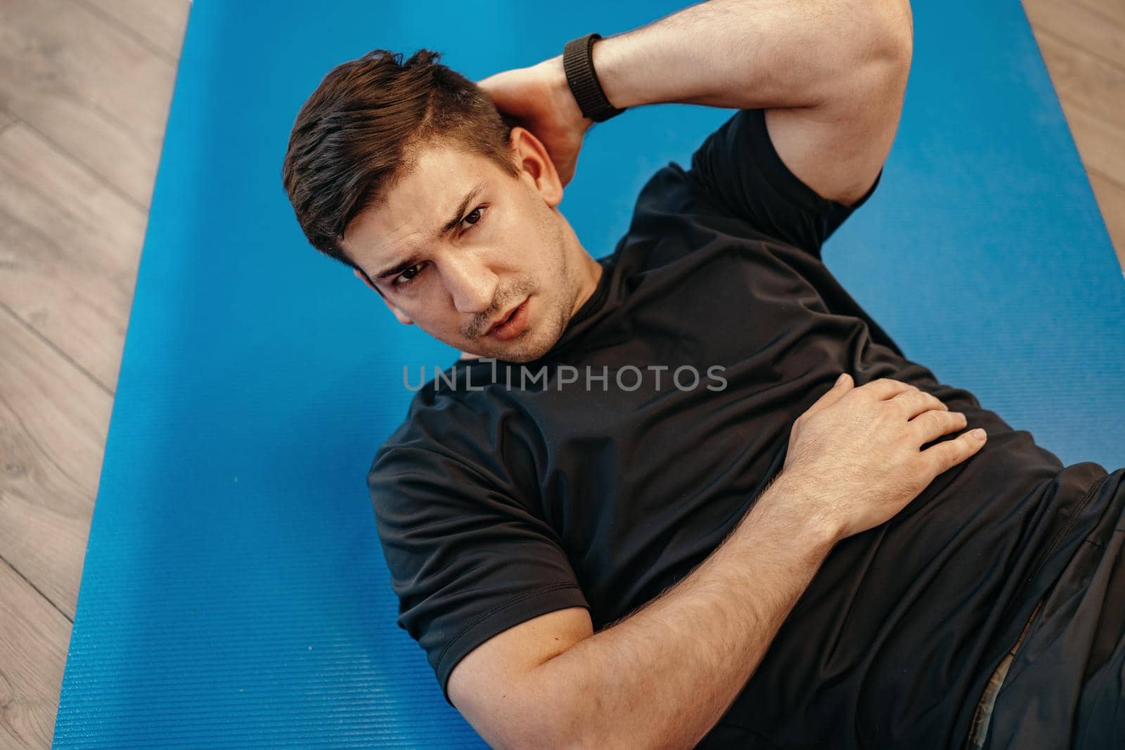 Young muscular caucasian handsome man doing abs exercises on a mat