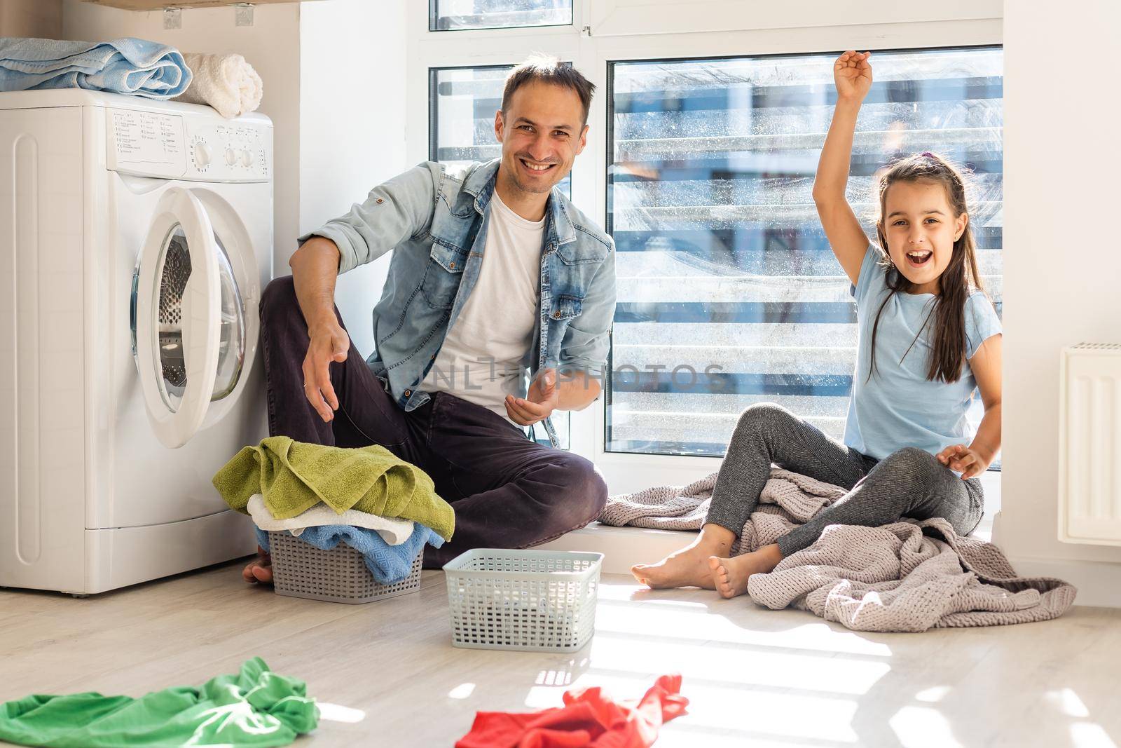 Happy family man father householder and child daughter in laundry with washing machine by Andelov13